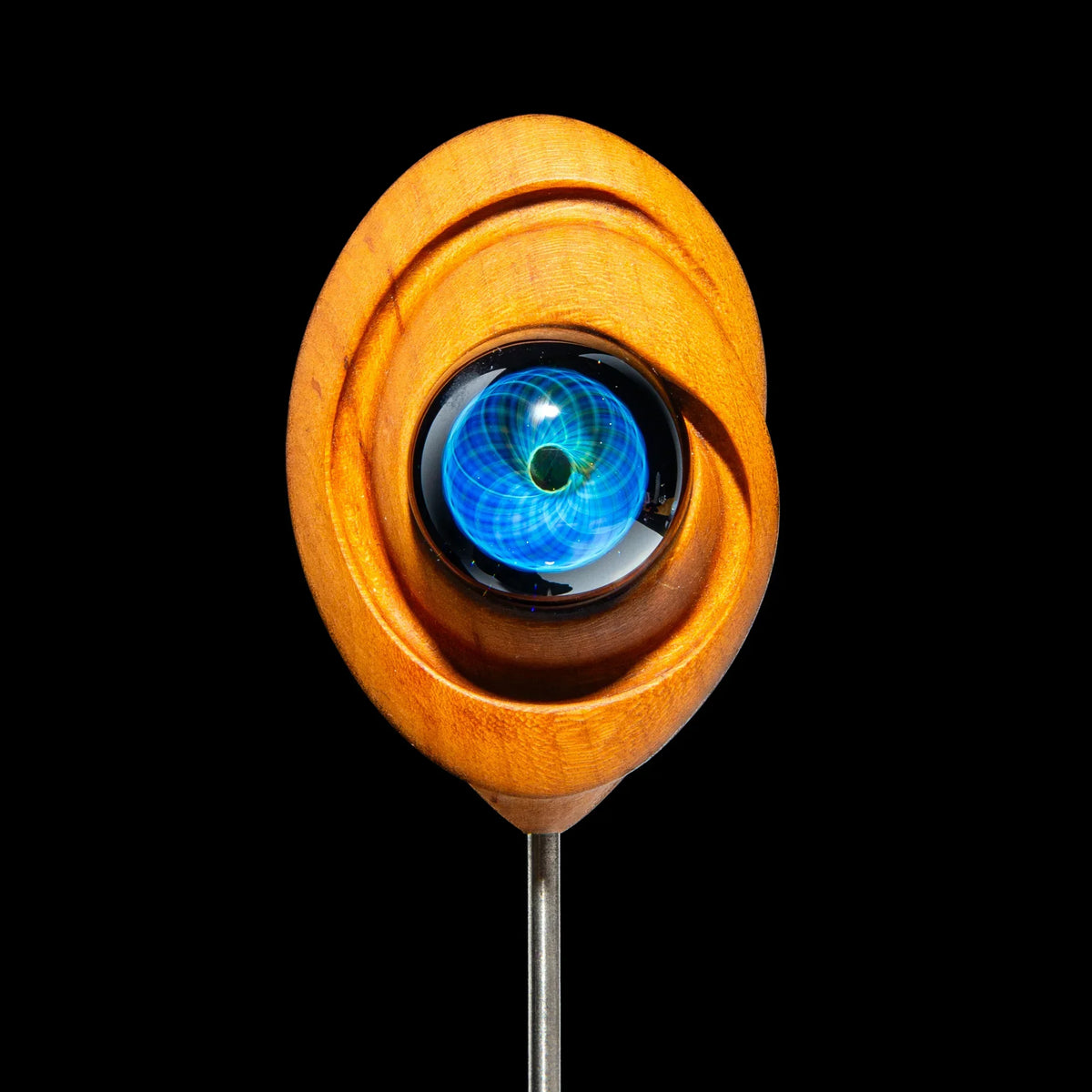 Glass dab tool with intricate blue design, set in a carved wooden holder against black background