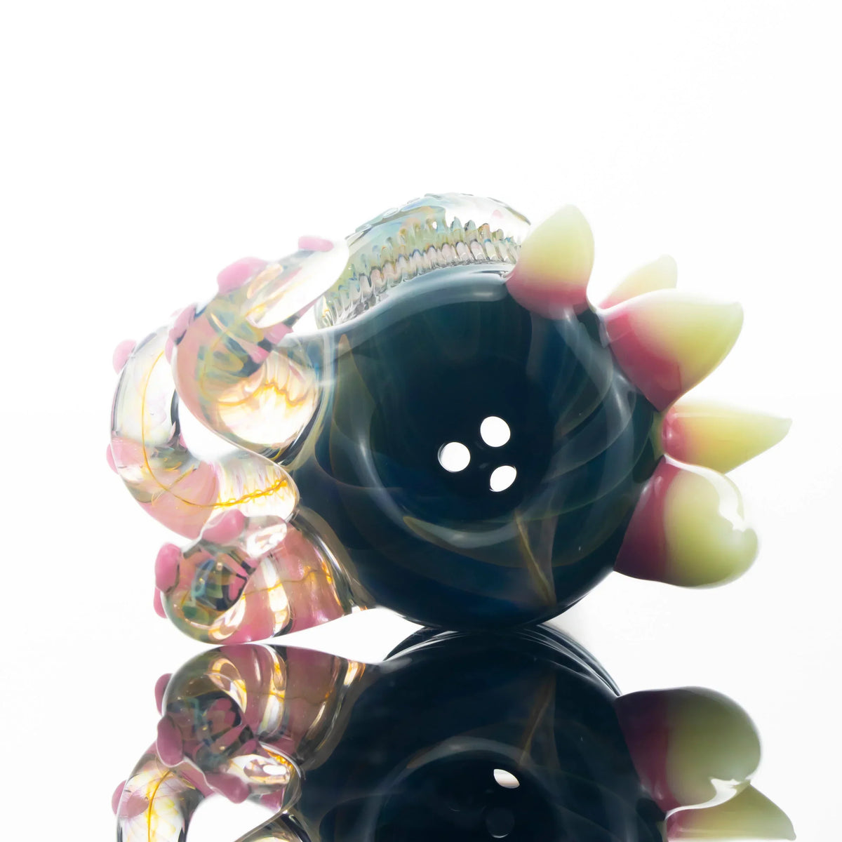 Colorful glass slide bowl with three holes, horn accents, and decorative swirls on reflective surface