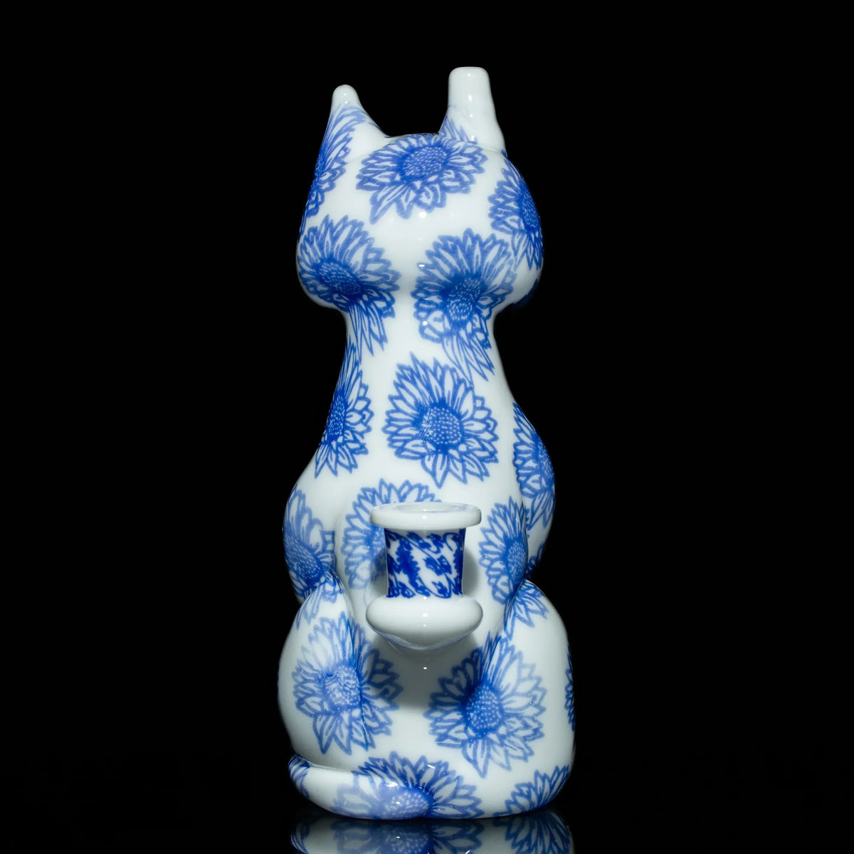 Blue and white cat-shaped glass pipe with floral patterns on black background