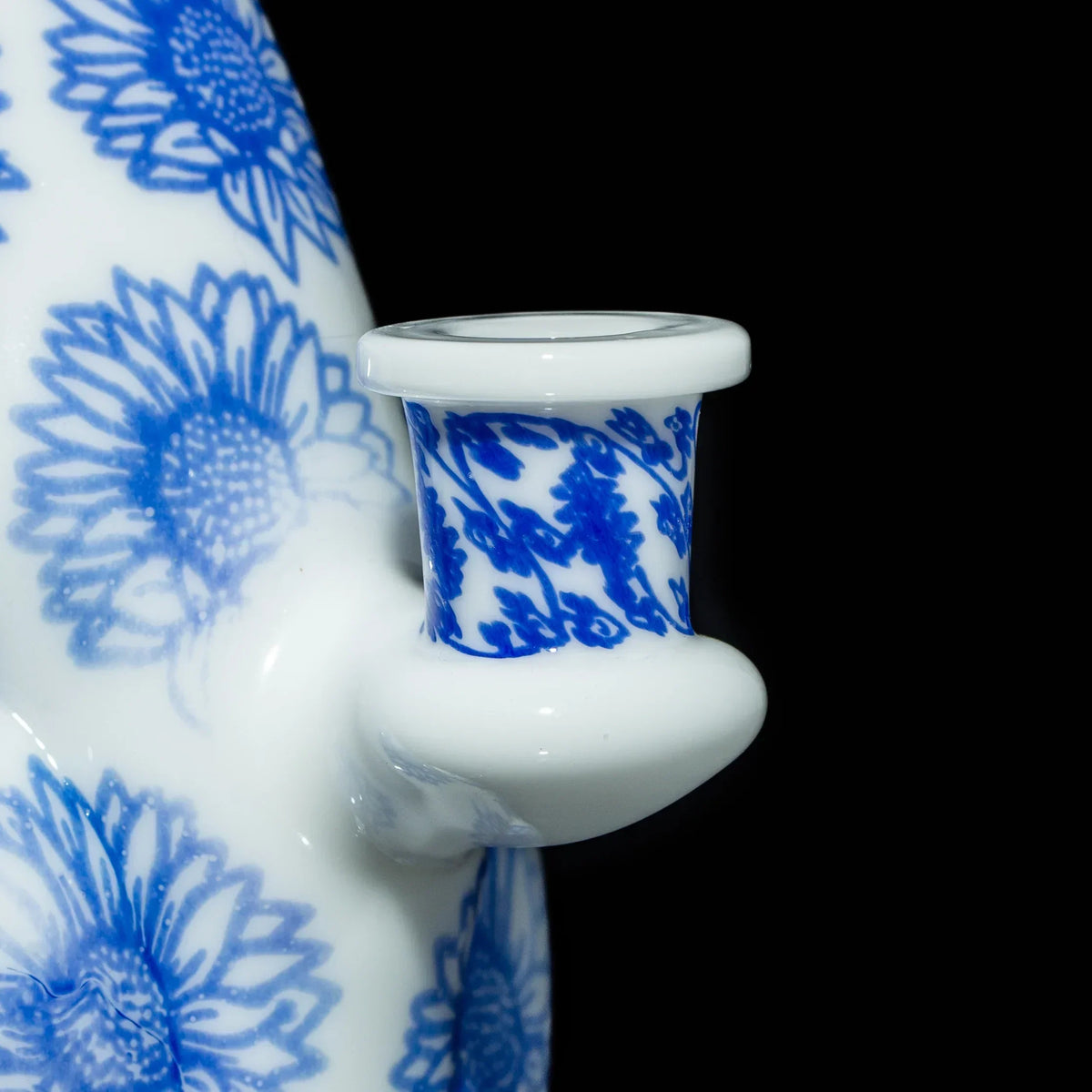 Close-up of white and blue floral-patterned glass bong joint with sunflowers