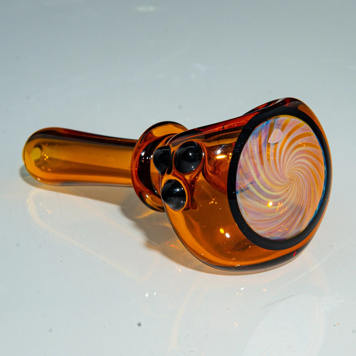 Amber glass hand pipe with black dots and a spiral pattern on the bowl