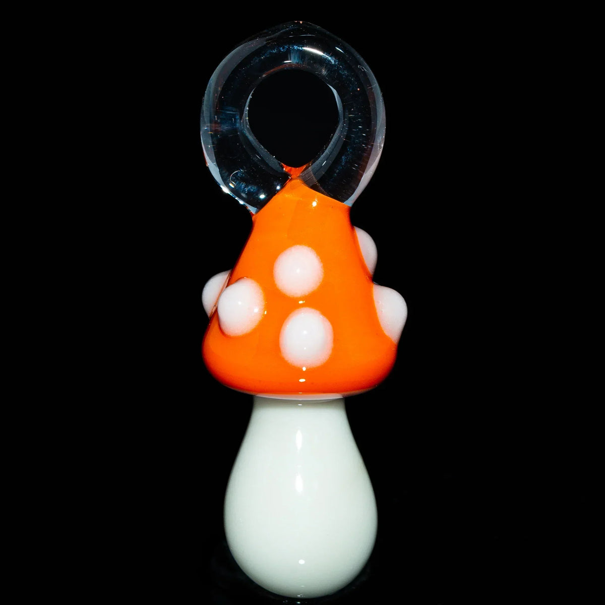 Handmade glass mushroom pendant with orange cap and white spots on black background