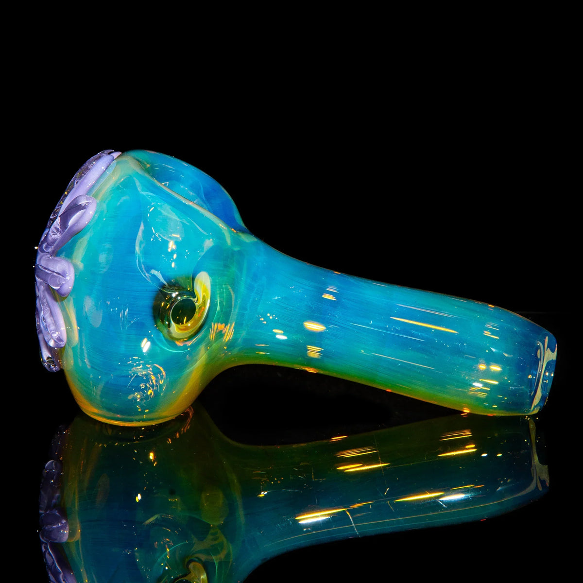 Handcrafted blue and yellow glass spoon pipe with purple flower accents on a black background.