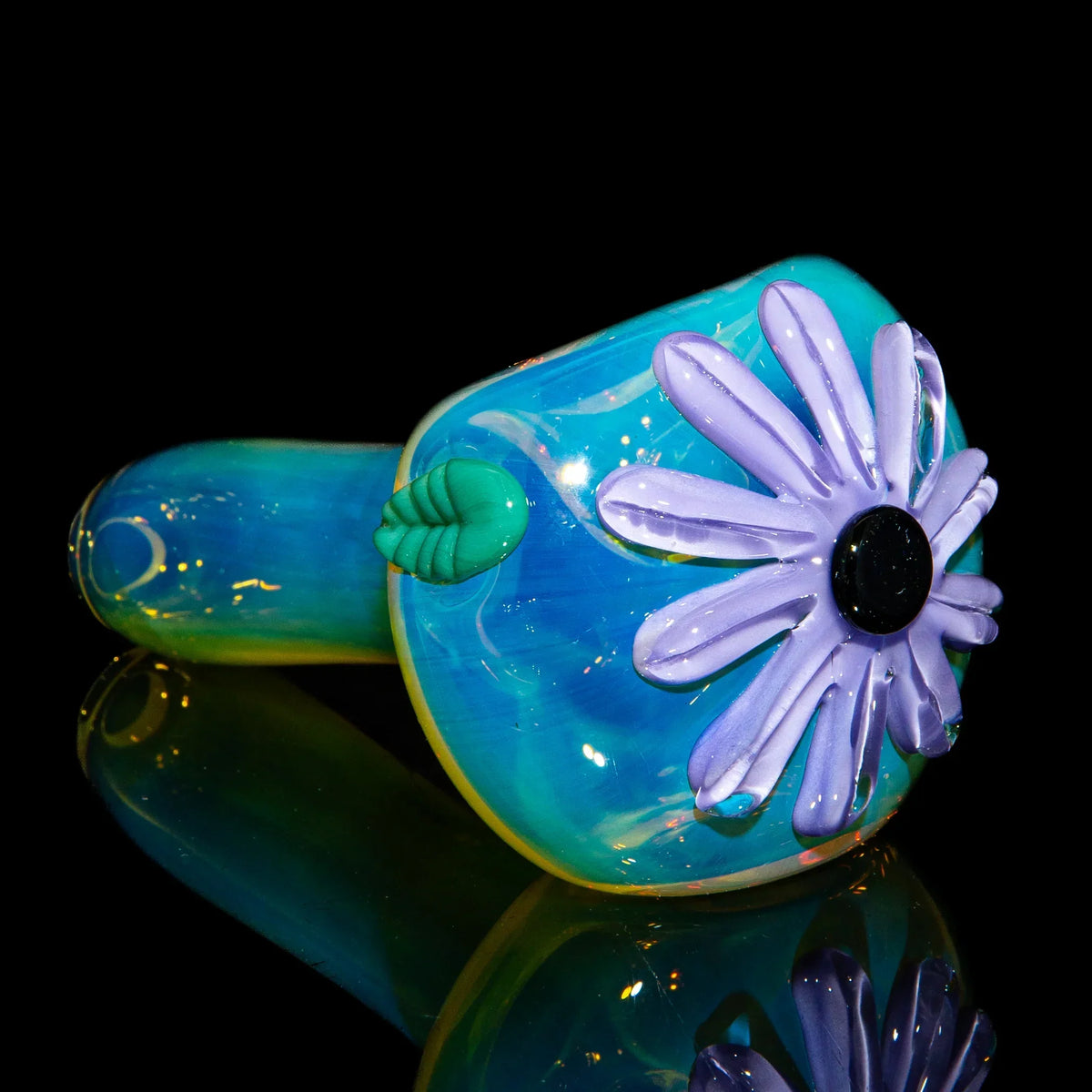 Handcrafted glass spoon pipe with purple flower design on blue fumed glass, reflective surface
