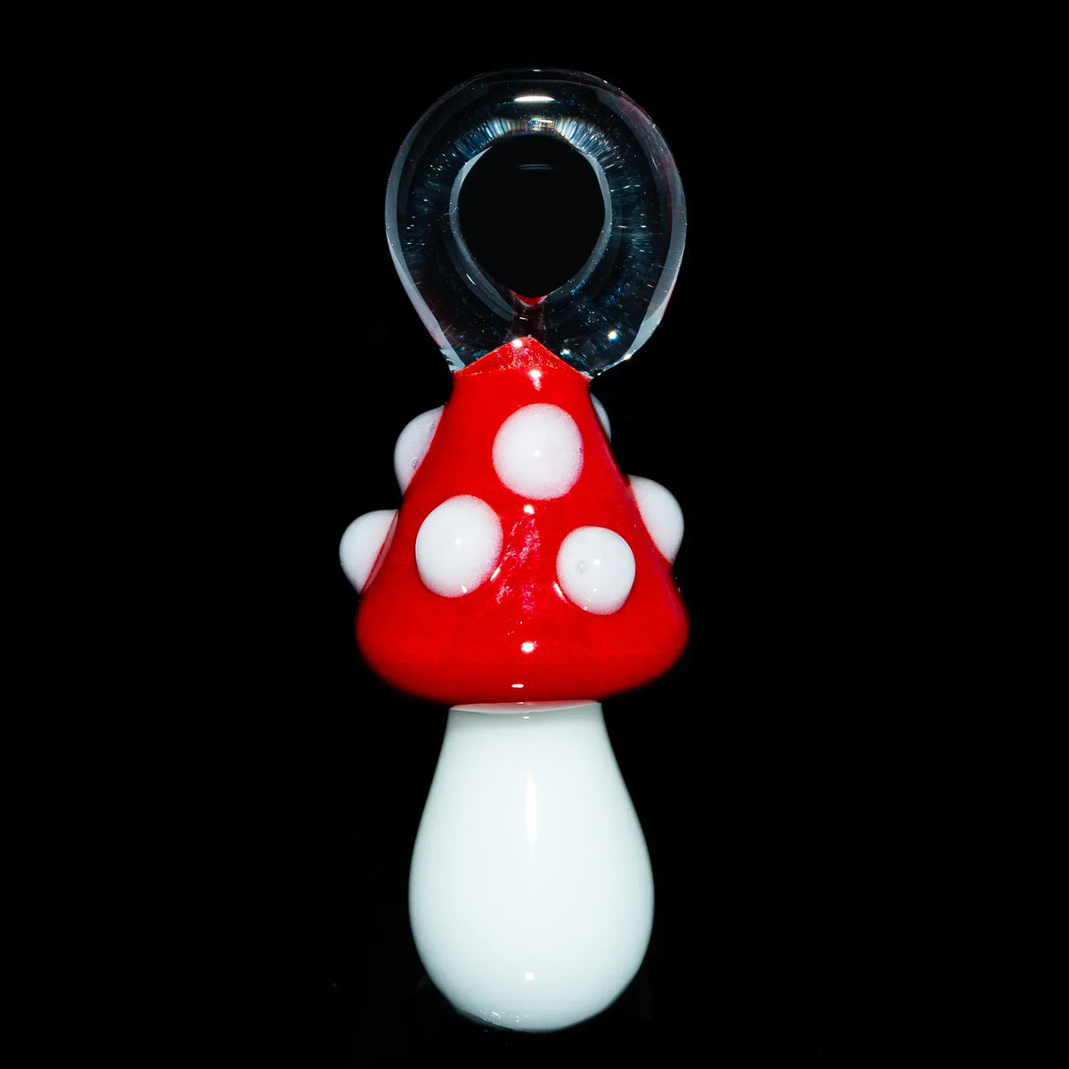 Handcrafted glass mushroom pendant with red cap and white spots on black background