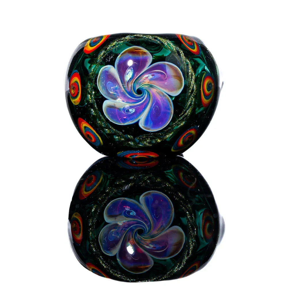 Colorful glass hand pipe with swirling flower design and rainbow accents on a reflective surface