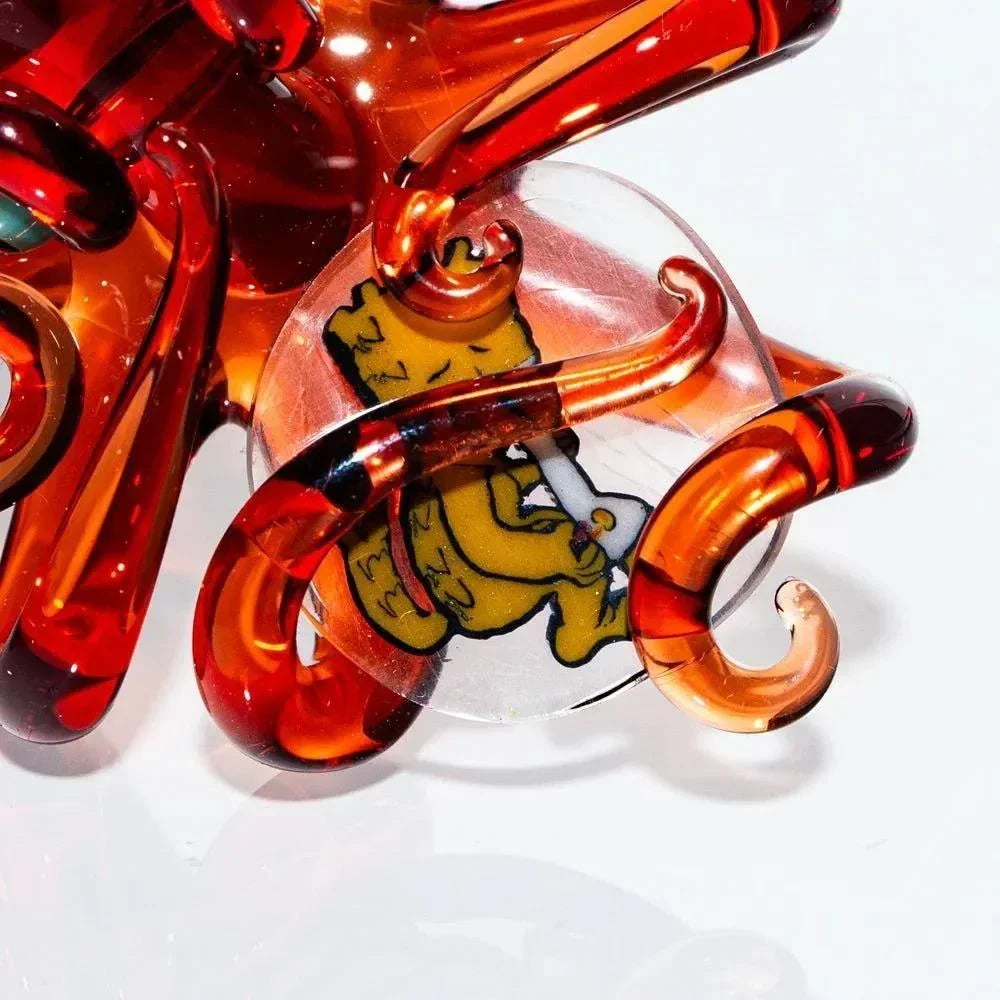 Close-up of intricate orange glass art piece with cartoon bear encased in clear marble