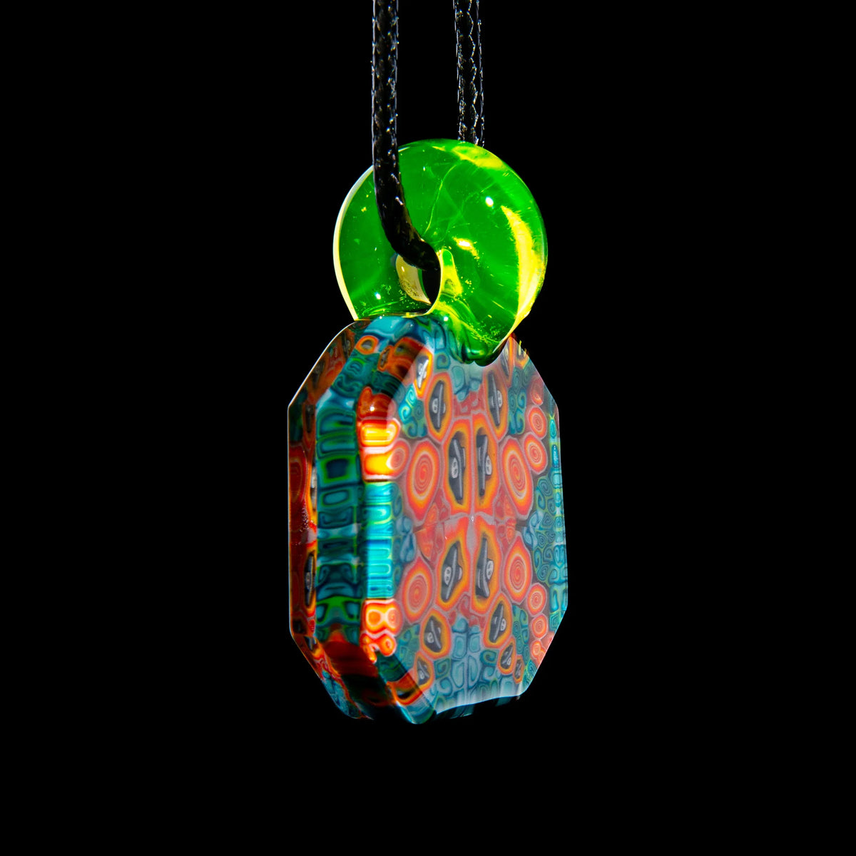 Colorful glass pendant with intricate pattern and neon green loop on black cord