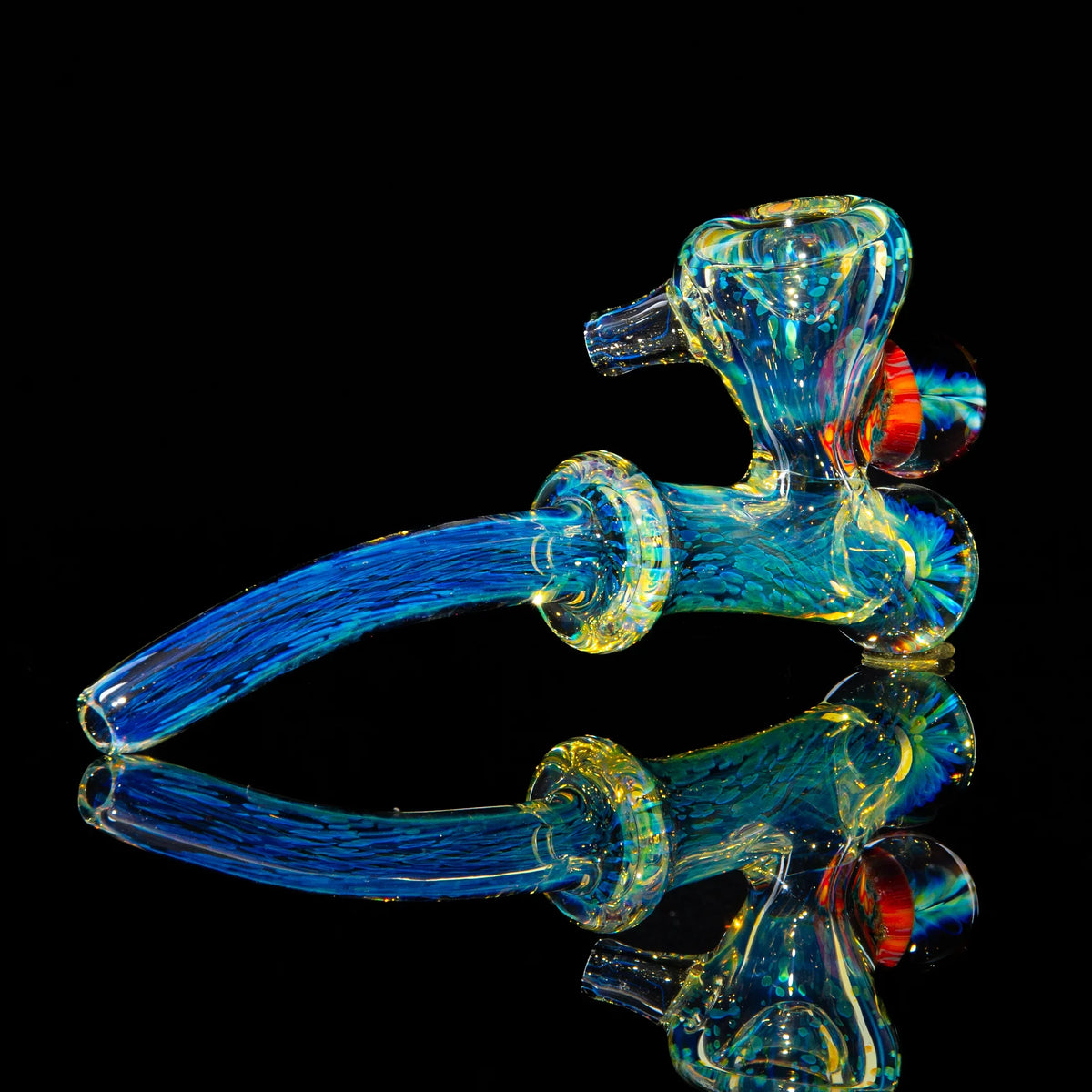 Colorful glass hand pipe with blue and yellow accents on a reflective black surface