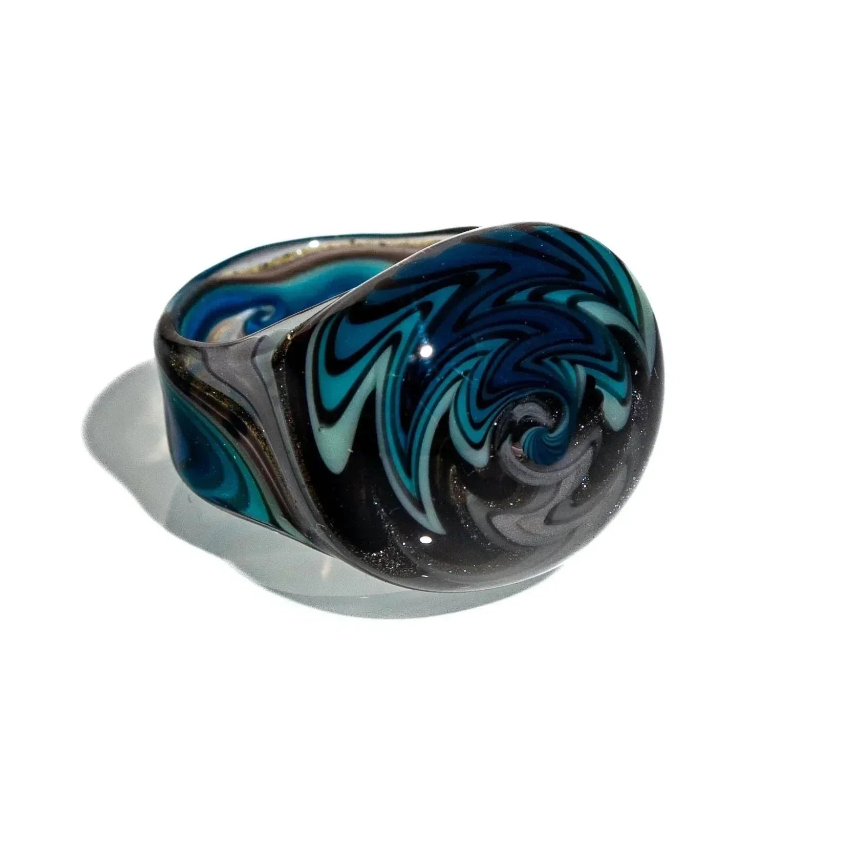 Hand-blown glass ring with black, blue, and teal swirl wig wag design on white background