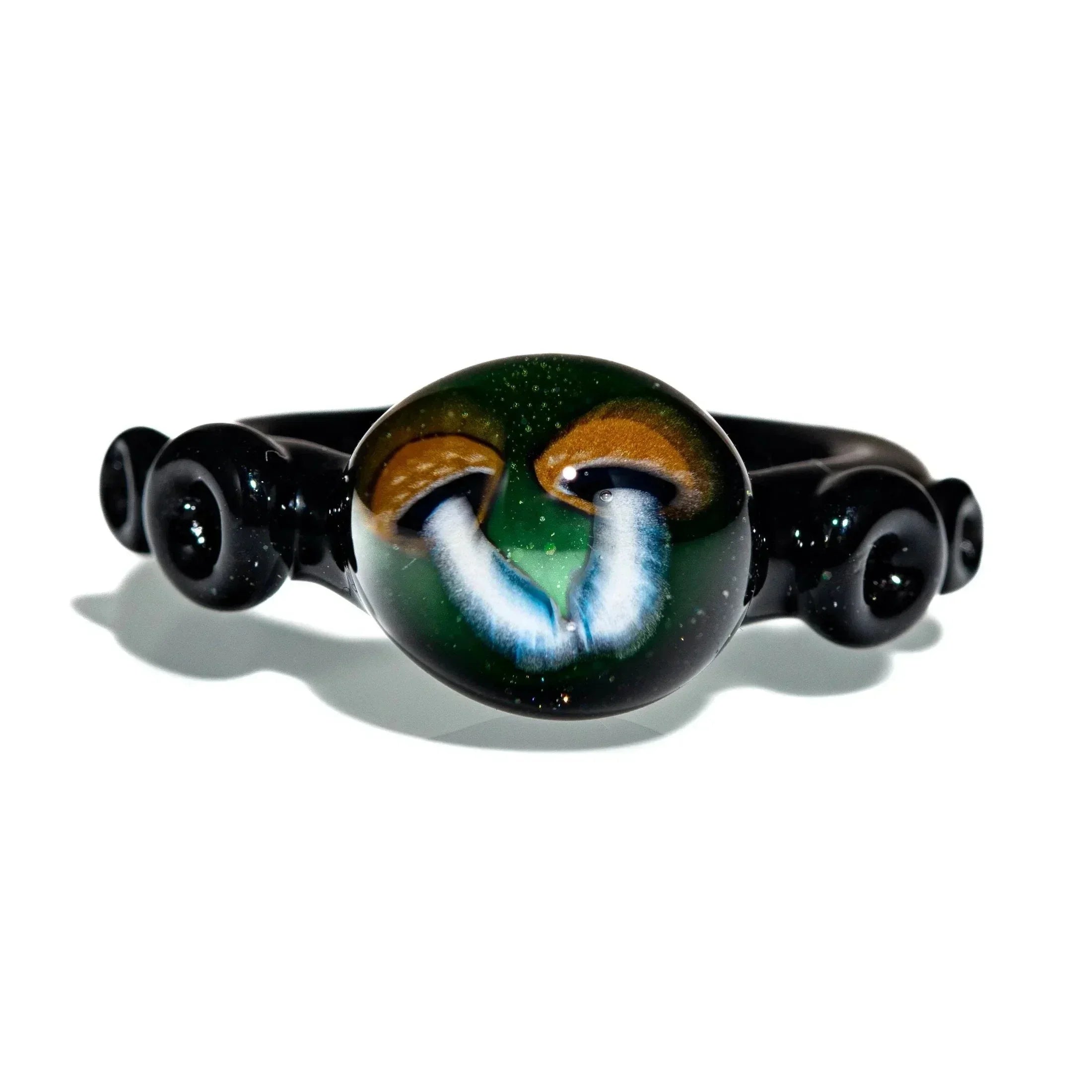 Handcrafted black glass ring with two detailed mushroom designs on a green background