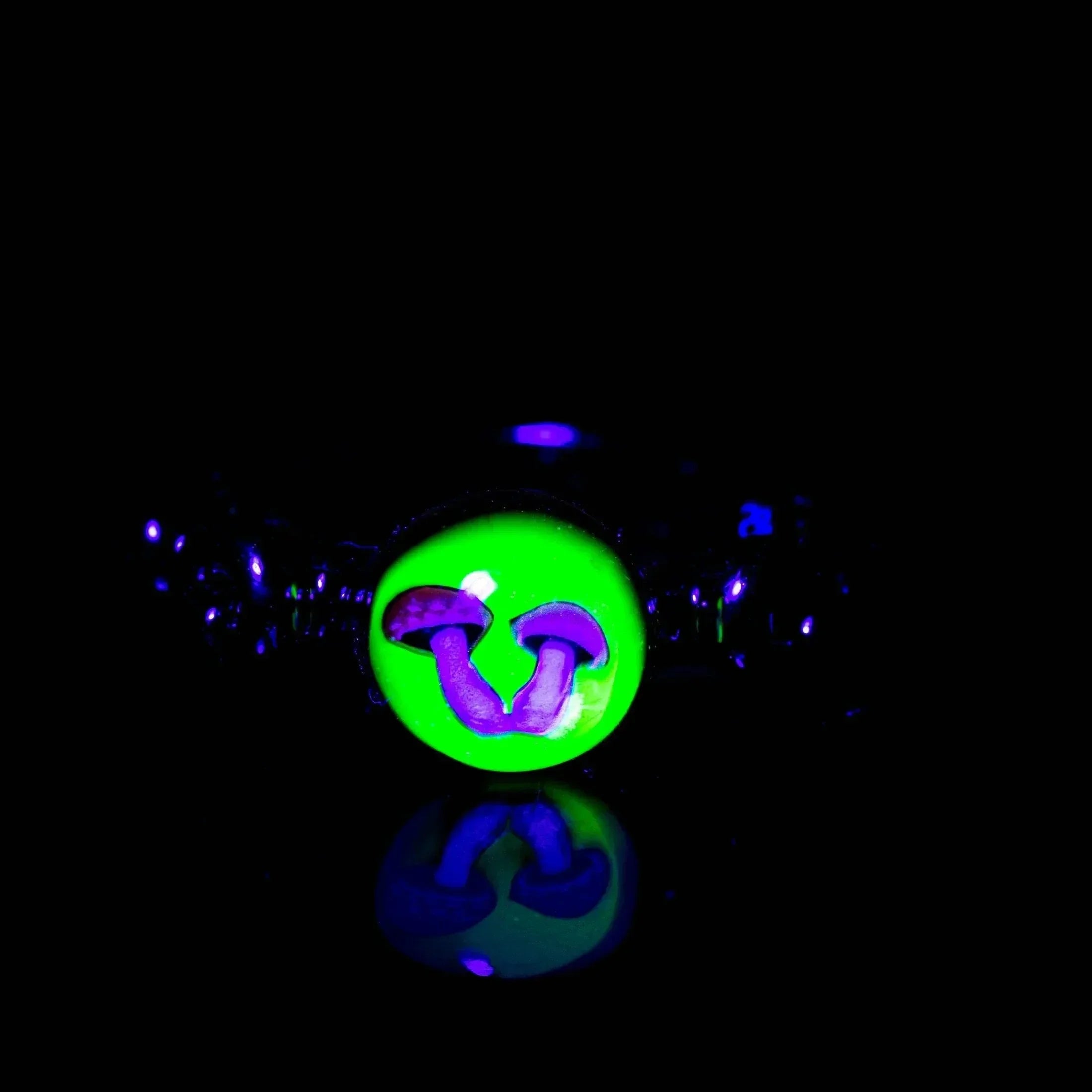 Blacklight glass ring with glowing green face and purple mushroom design