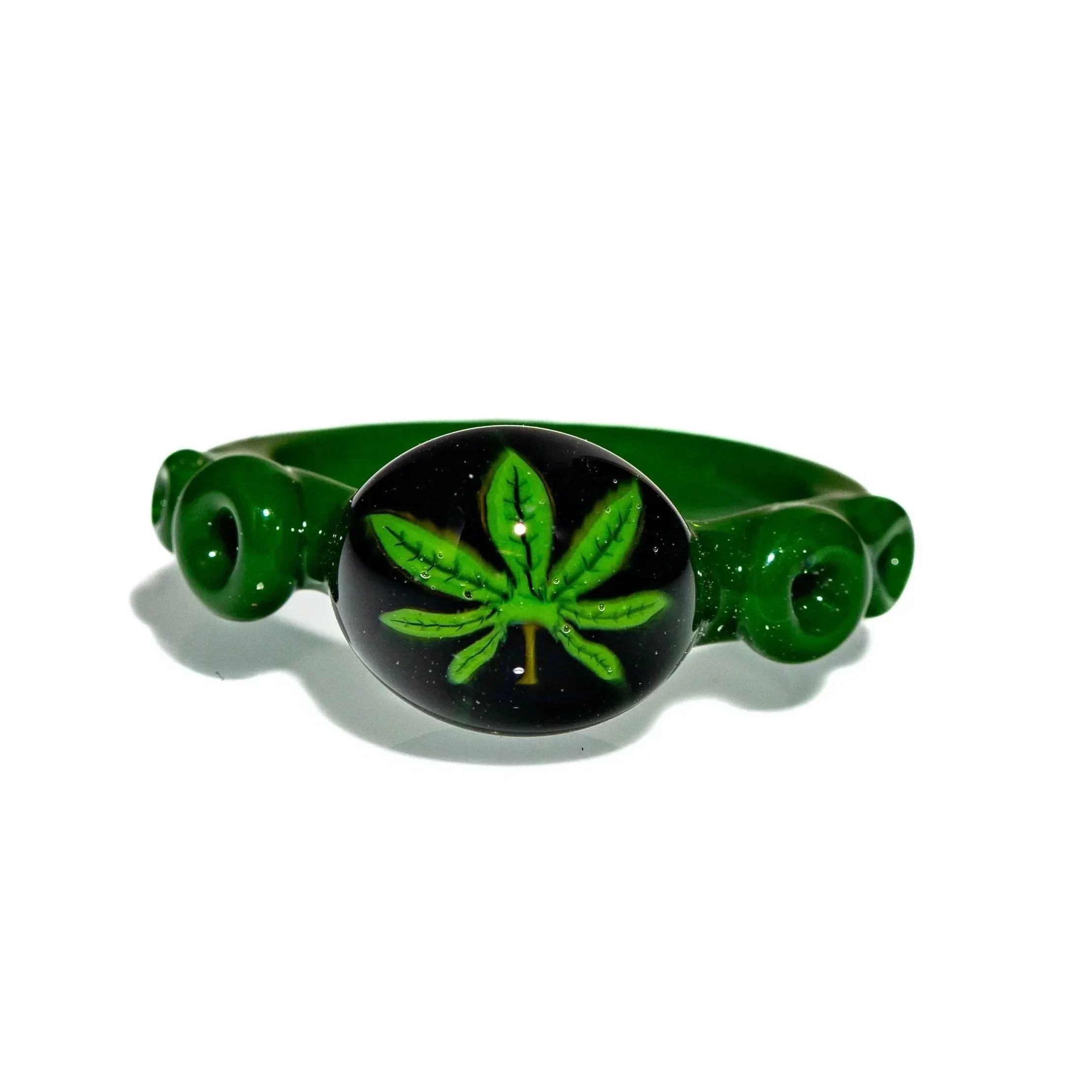 Green glass ring with a detailed leaf design on the front, isolated on white background.