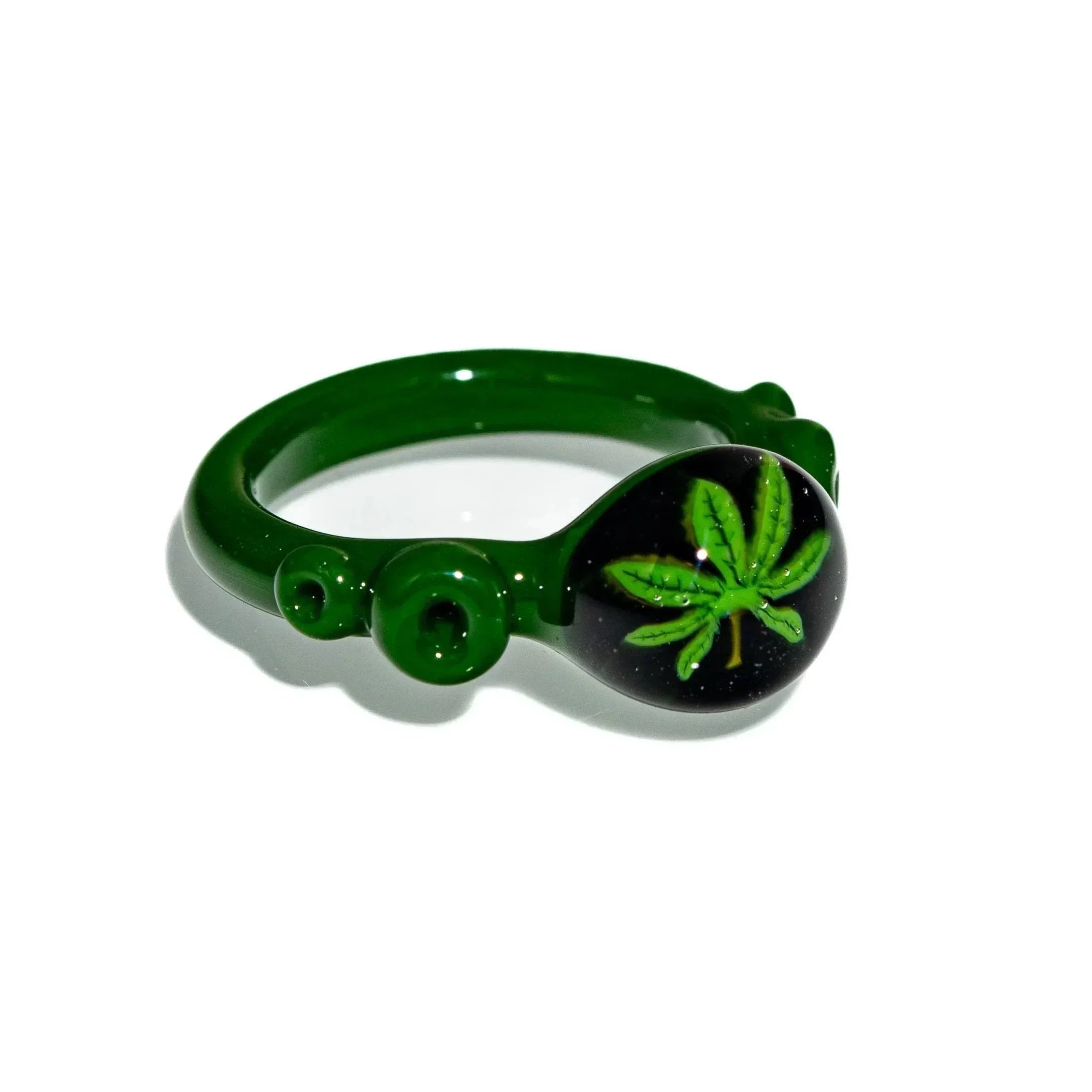 Green glass ring with a detailed leaf design on a black background, artistic accessory