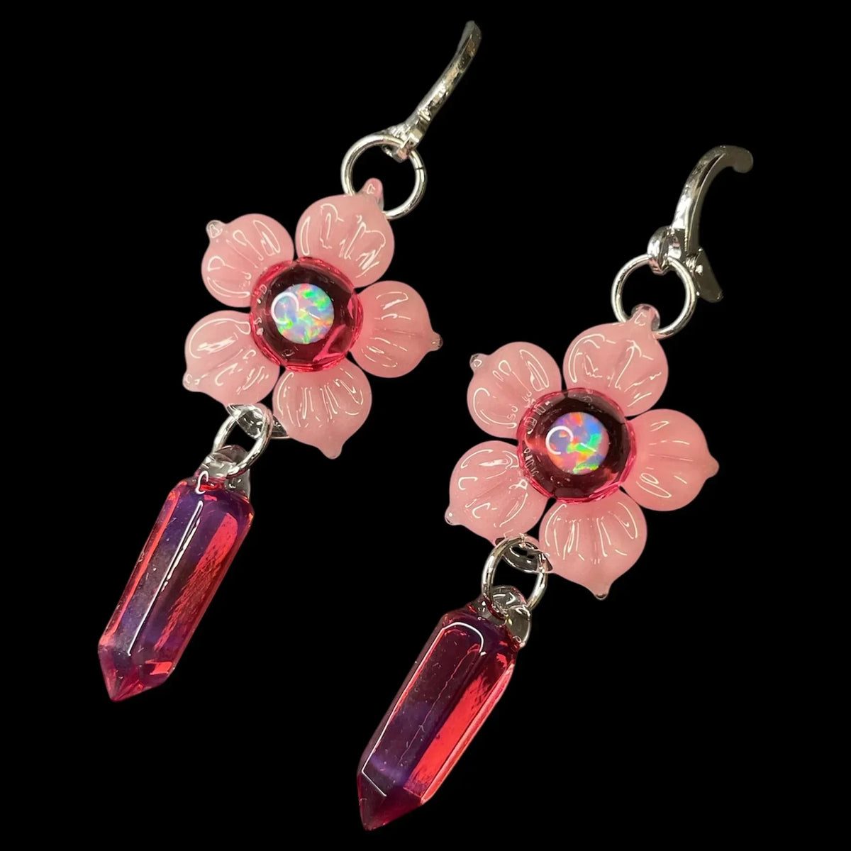 Pink flower earrings with iridescent centers and red crystal point drops on black background