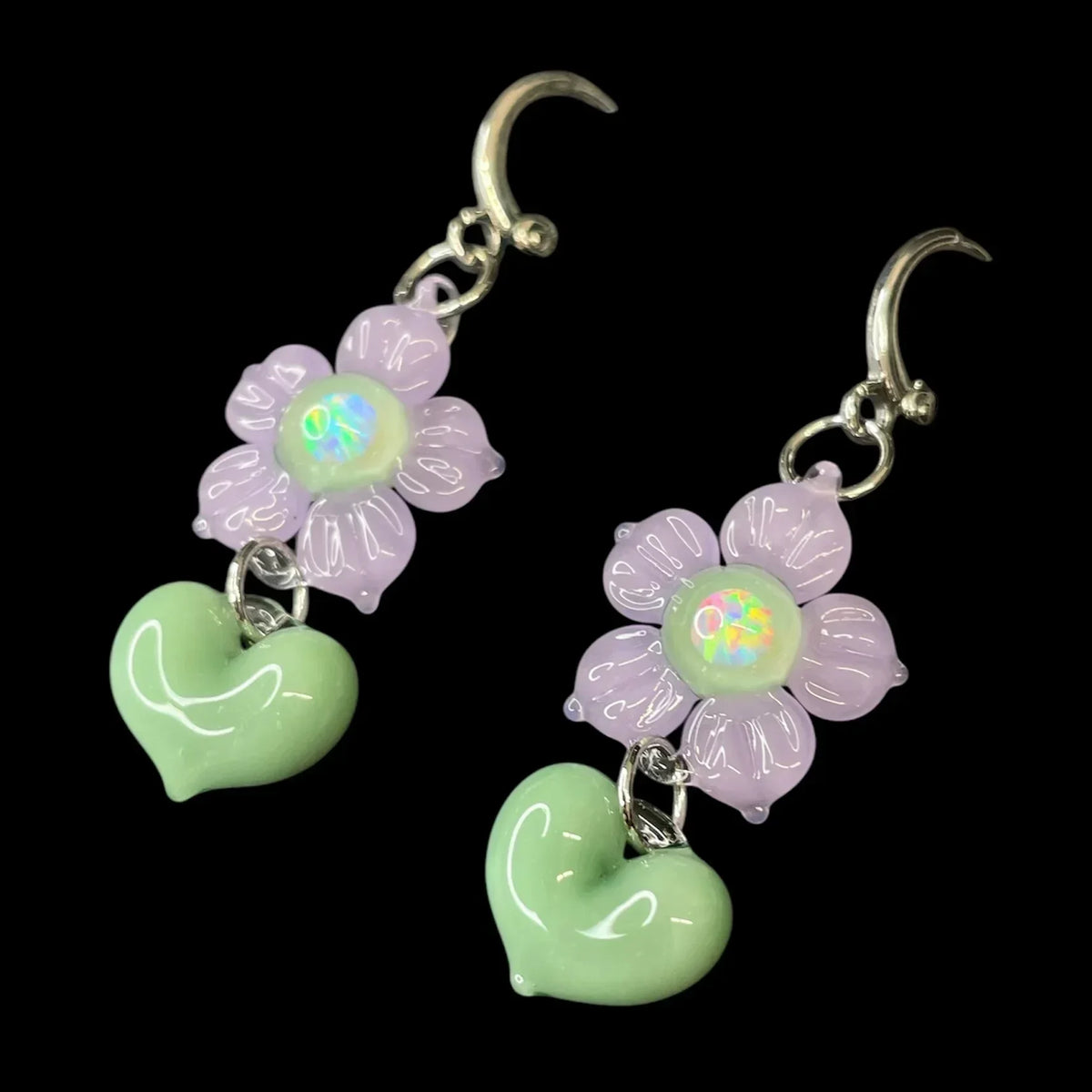 Handmade glass earrings with purple flower and green heart charms on silver hooks