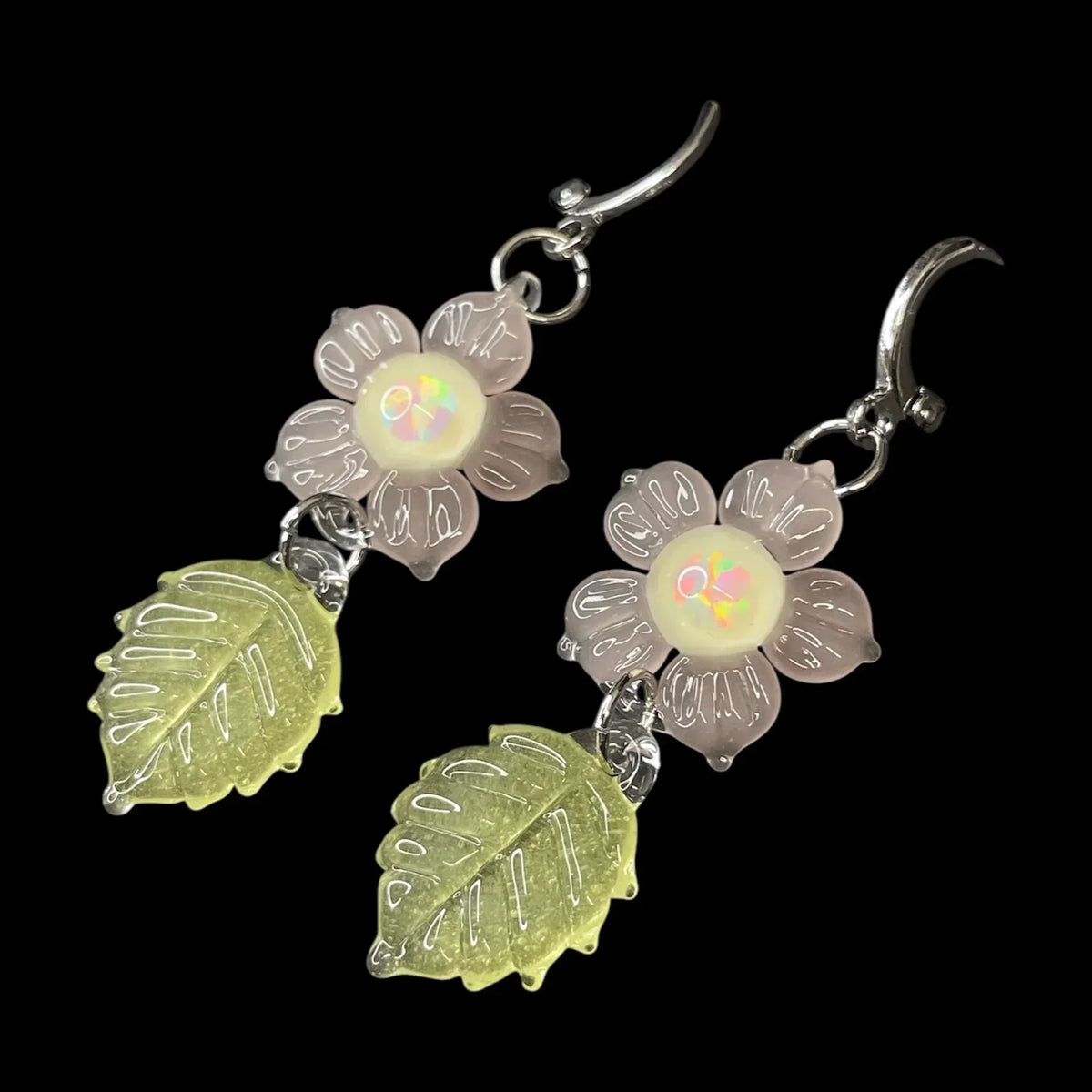 Handcrafted glass earrings with pink flower and yellow leaf design on black background