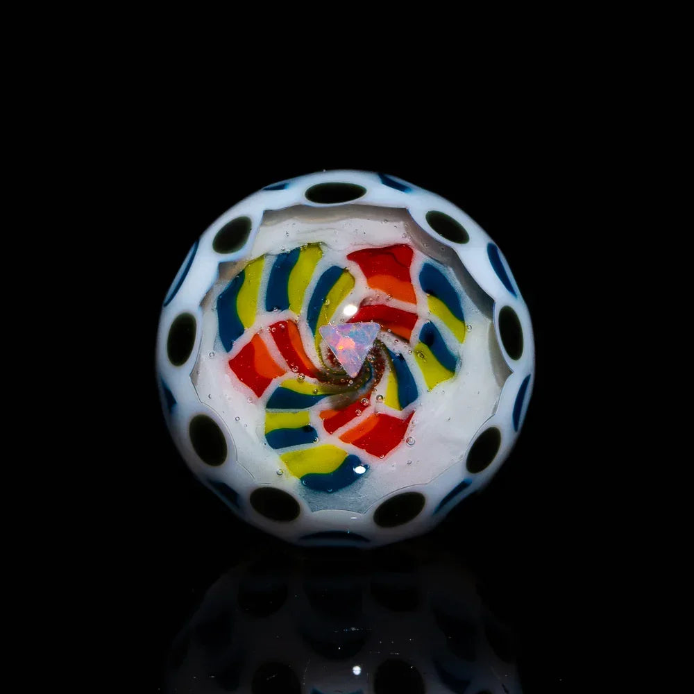 Colorful glass marble with spiral opal inlay and polka dot accents on black background