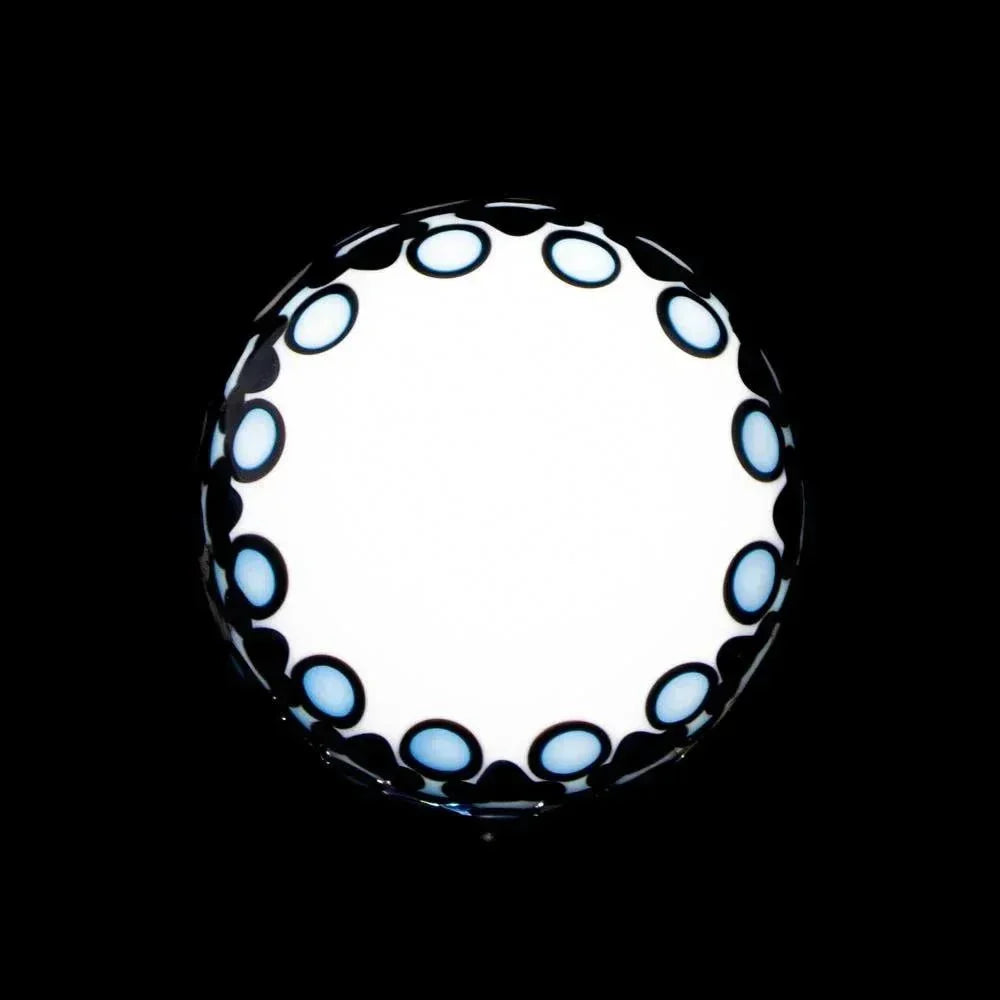 Round glass marble with black and blue dot pattern on a white center, against black background
