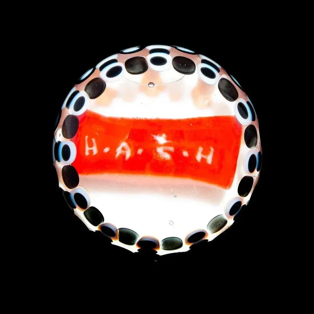 Handcrafted glass marble with HASH text, black and white dot accents on clear background