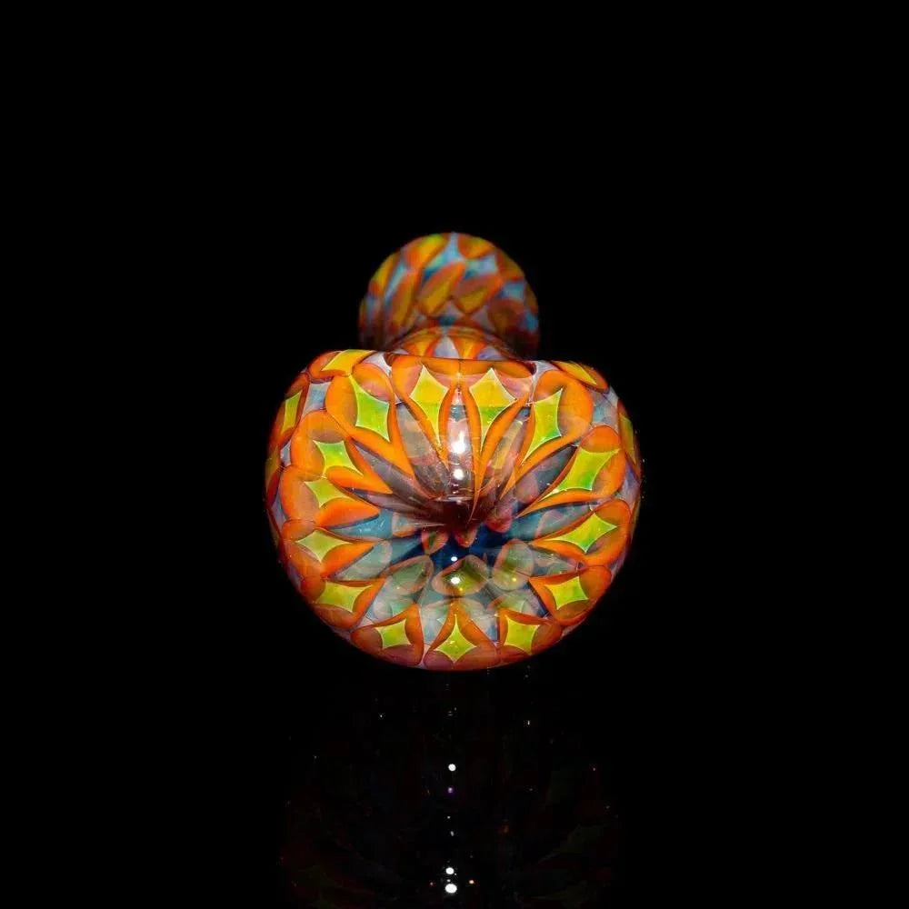 Colorful hand-blown glass spoon pipe with vibrant geometric patterns on a black background