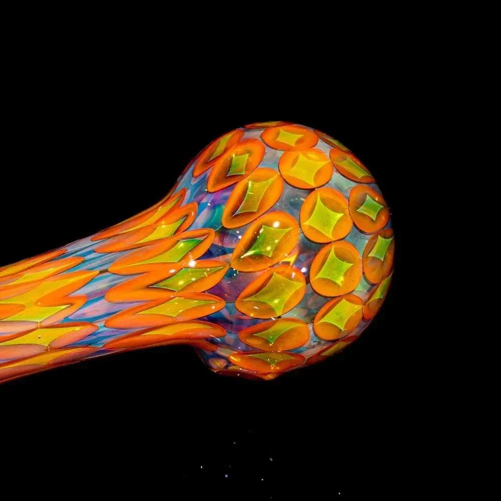 Colorful glass spoon pipe with vibrant orange and yellow geometric patterns on black background