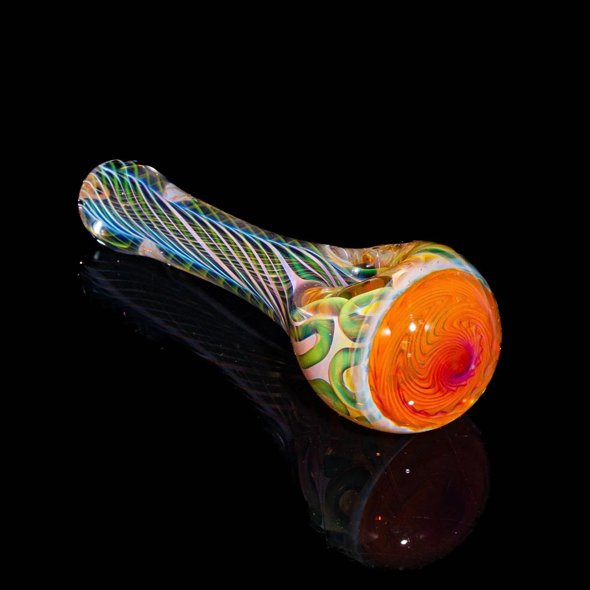 Colorful hand-blown glass spoon pipe with orange and green patterns on a black background.