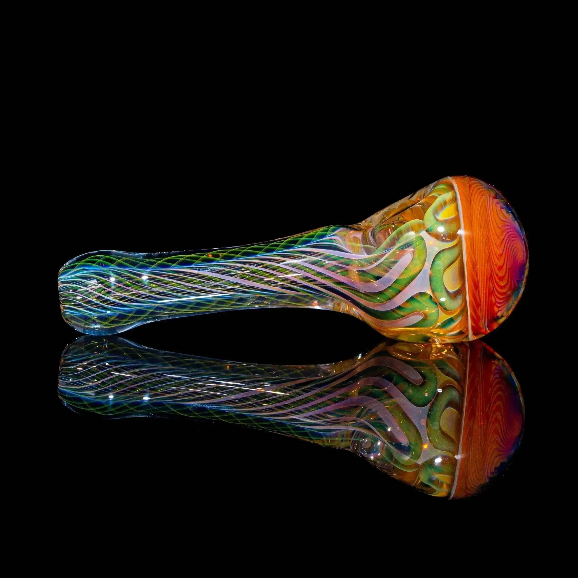 Colorful handblown glass spoon pipe with swirling patterns on a black reflective surface