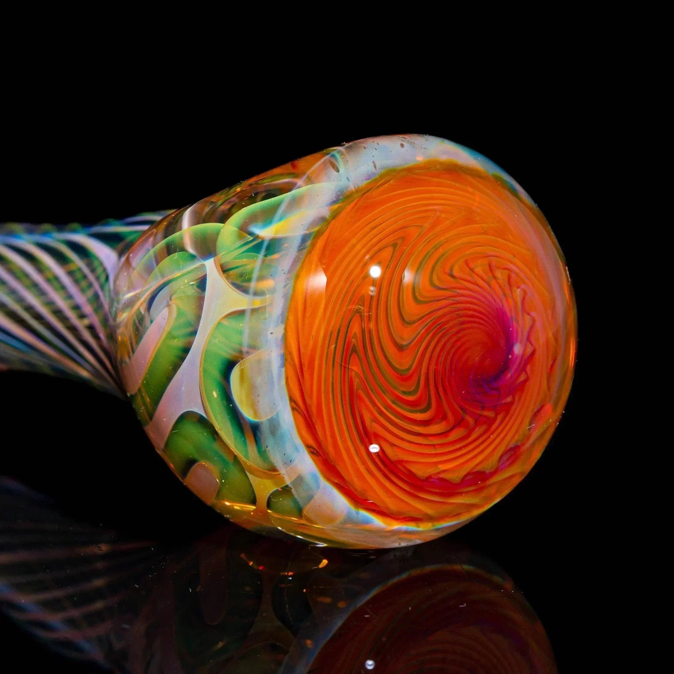Colorful glass spoon pipe with orange and green swirled design on black background
