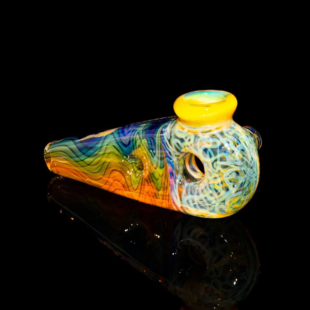 Colorful hand-blown glass pipe with wig wag and squiggle patterns on black background