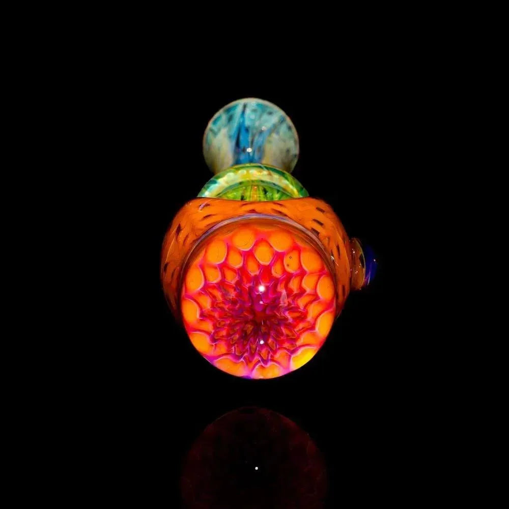 Colorful glass spoon pipe with vibrant honeycomb implosion design on black background