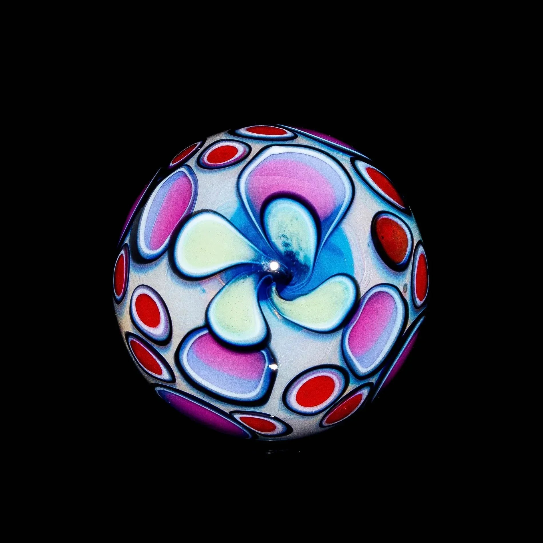 Colorful glass marble with pastel swirl and red dot patterns on a black background