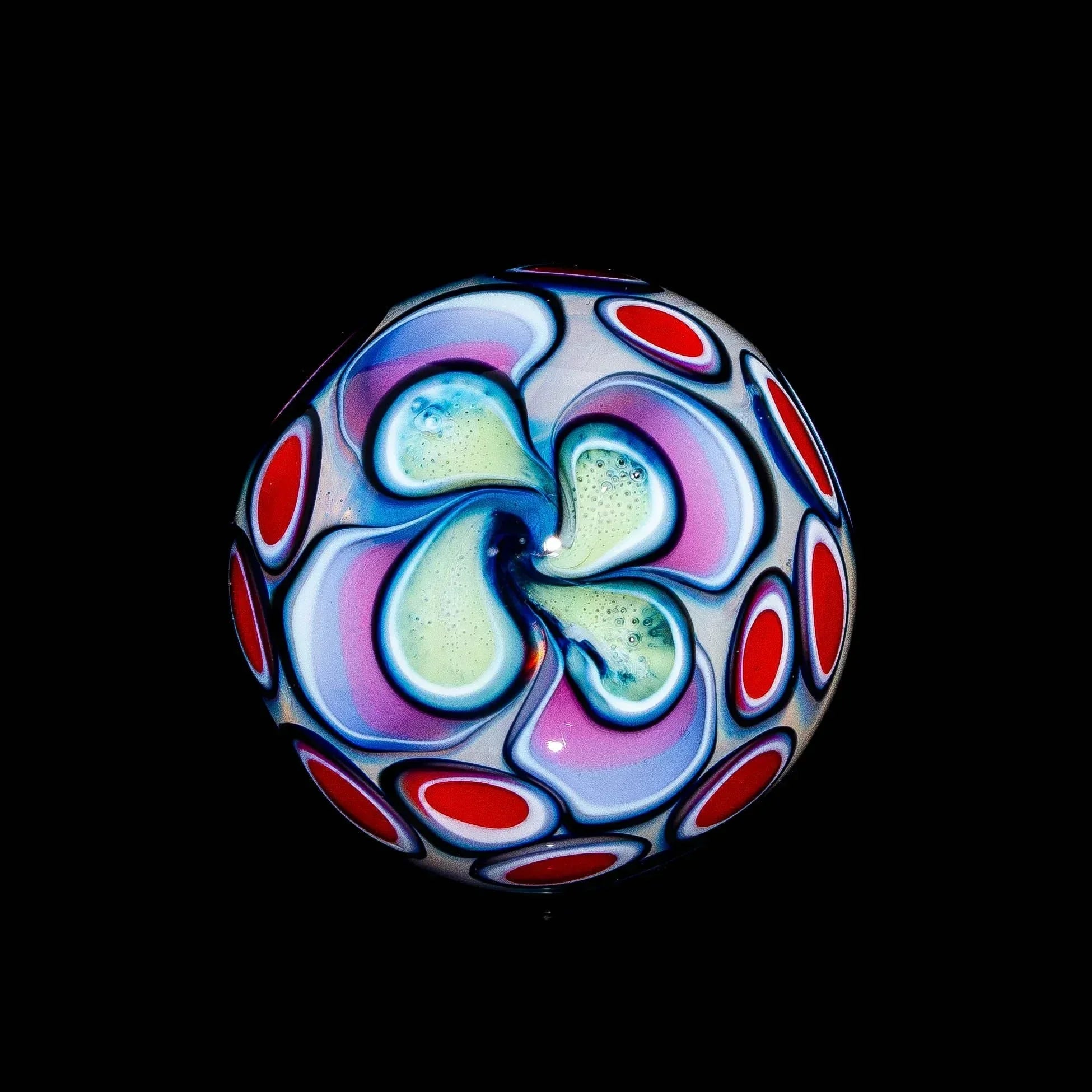 Hand-blown glass marble with pastel swirl and red dot pattern on black background
