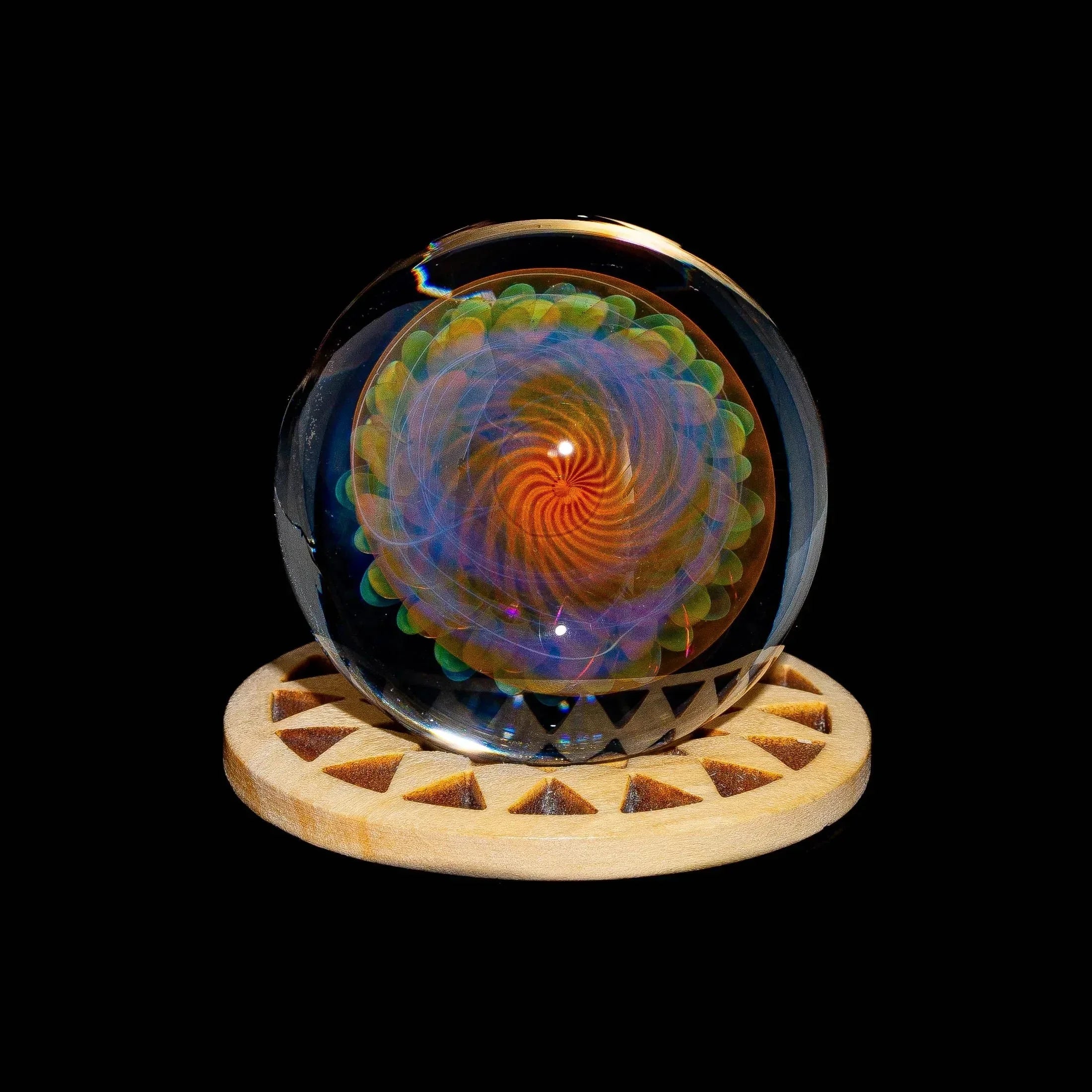 Colorful glass marble with swirling pattern on wooden display stand, black background
