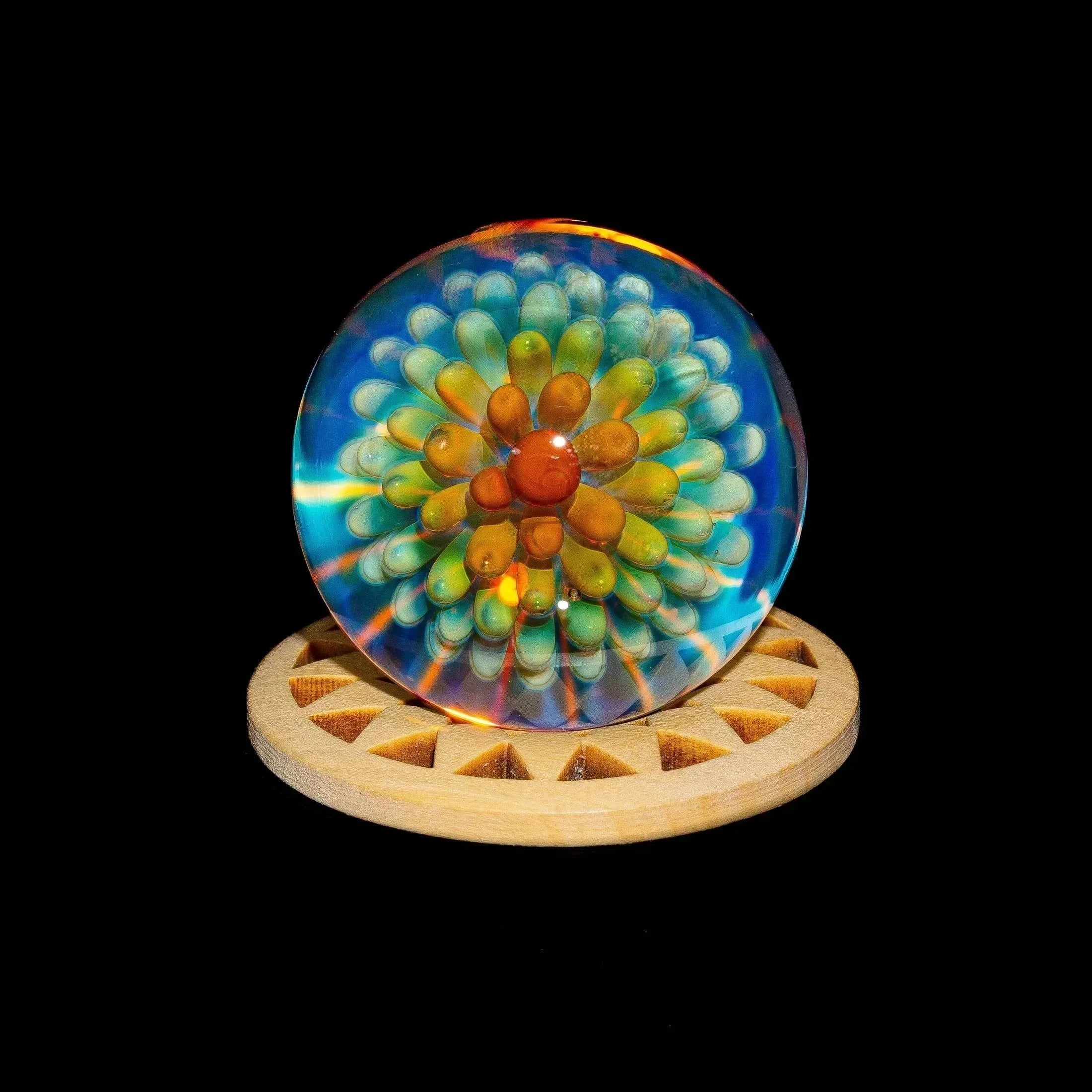 Colorful glass marble with atomic implosion art design on a wooden stand