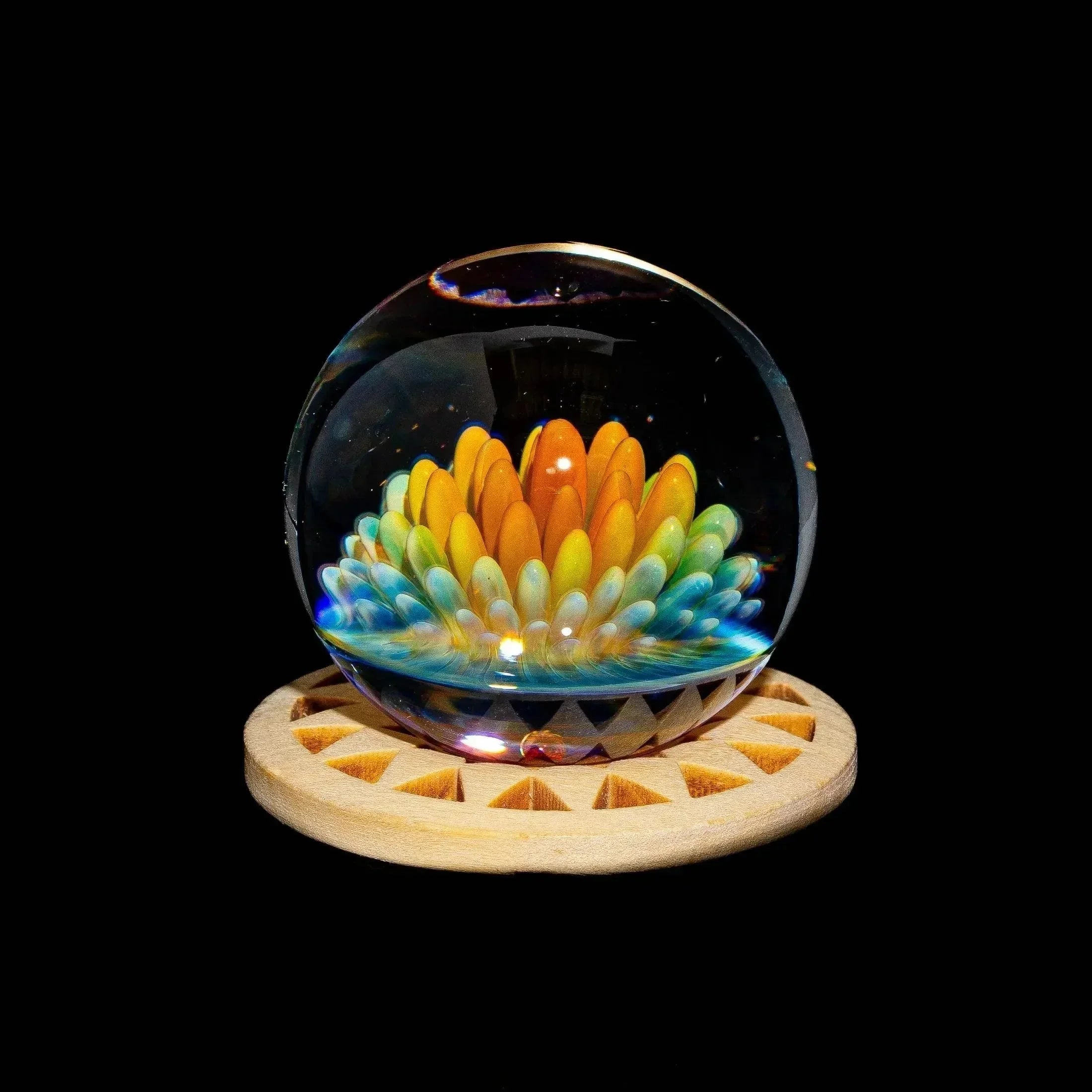 Handmade glass art marble with colorful flower design on a wooden stand, black background