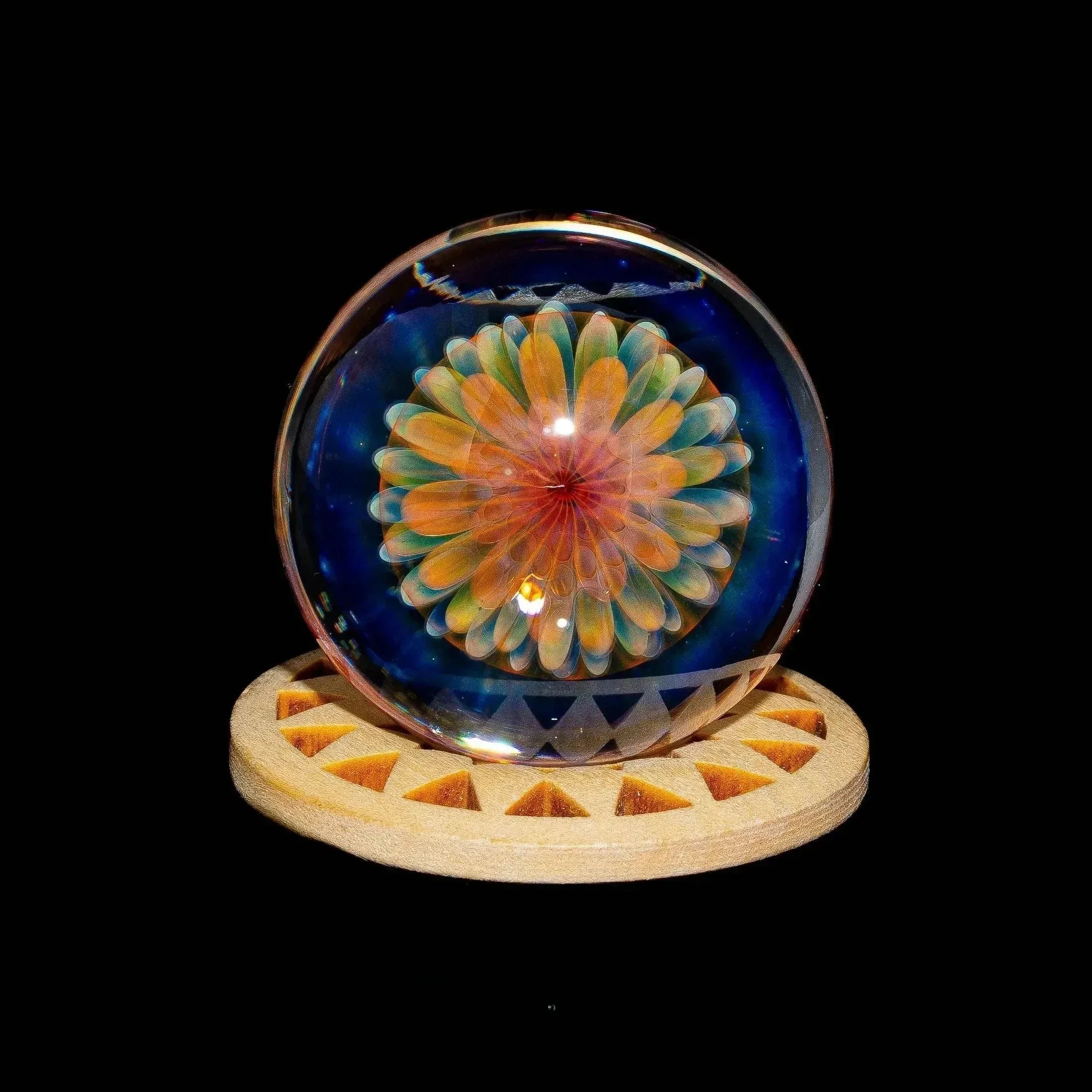 Handcrafted glass marble with vibrant flower design on a wooden stand, smoke shop art