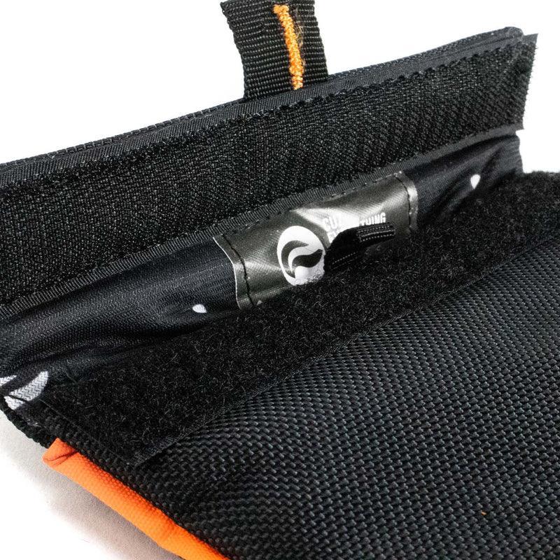 Close-up of a black and orange padded pouch with Velcro closure, textured exterior
