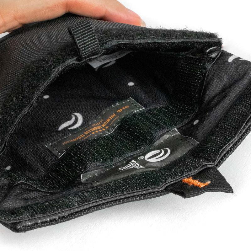 Closeup of open black padded pouch with soft lining and hook-and-loop closure, hand holding edge