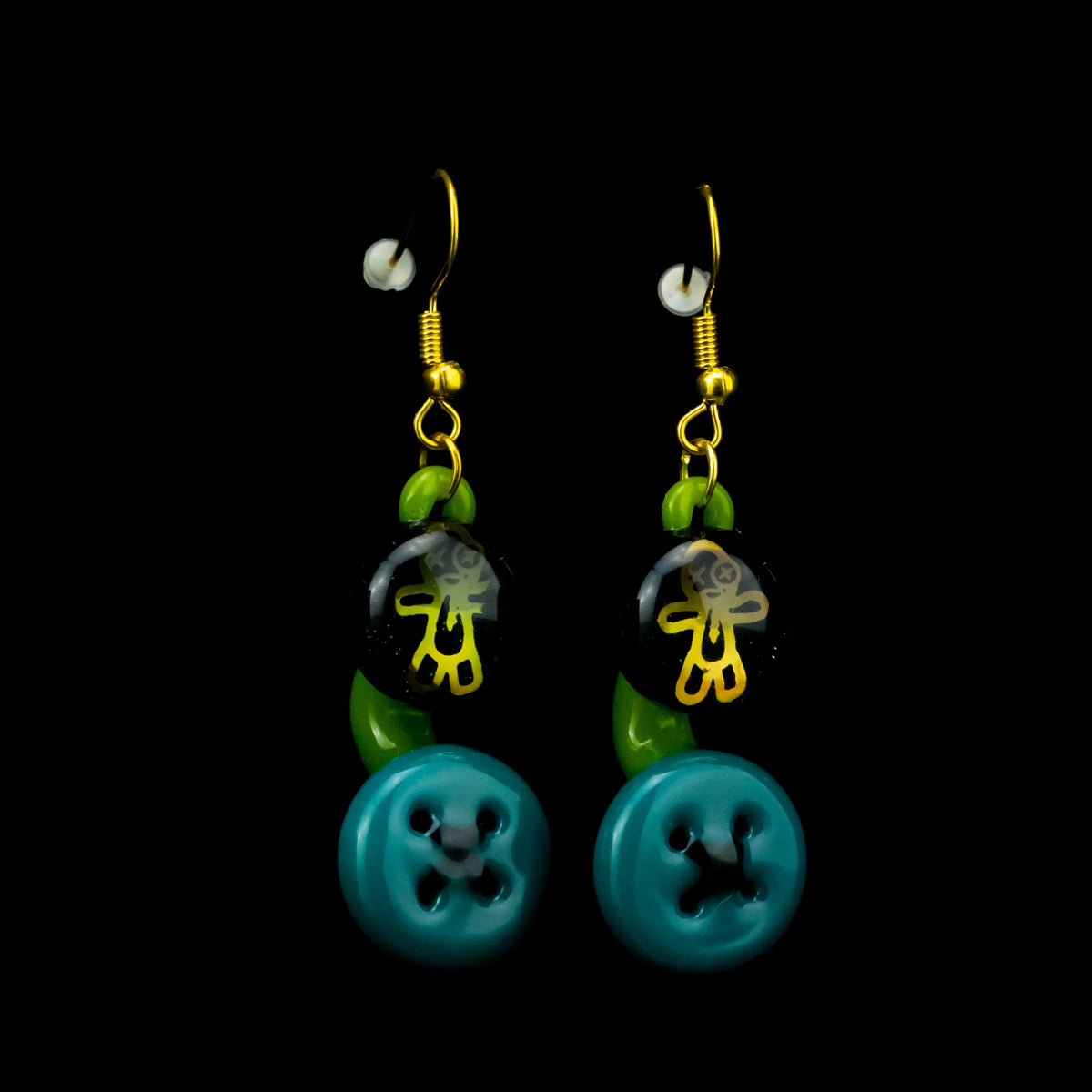 Handmade glass earrings with gold hooks, green accents, black beads with yellow figure, and blue button design.