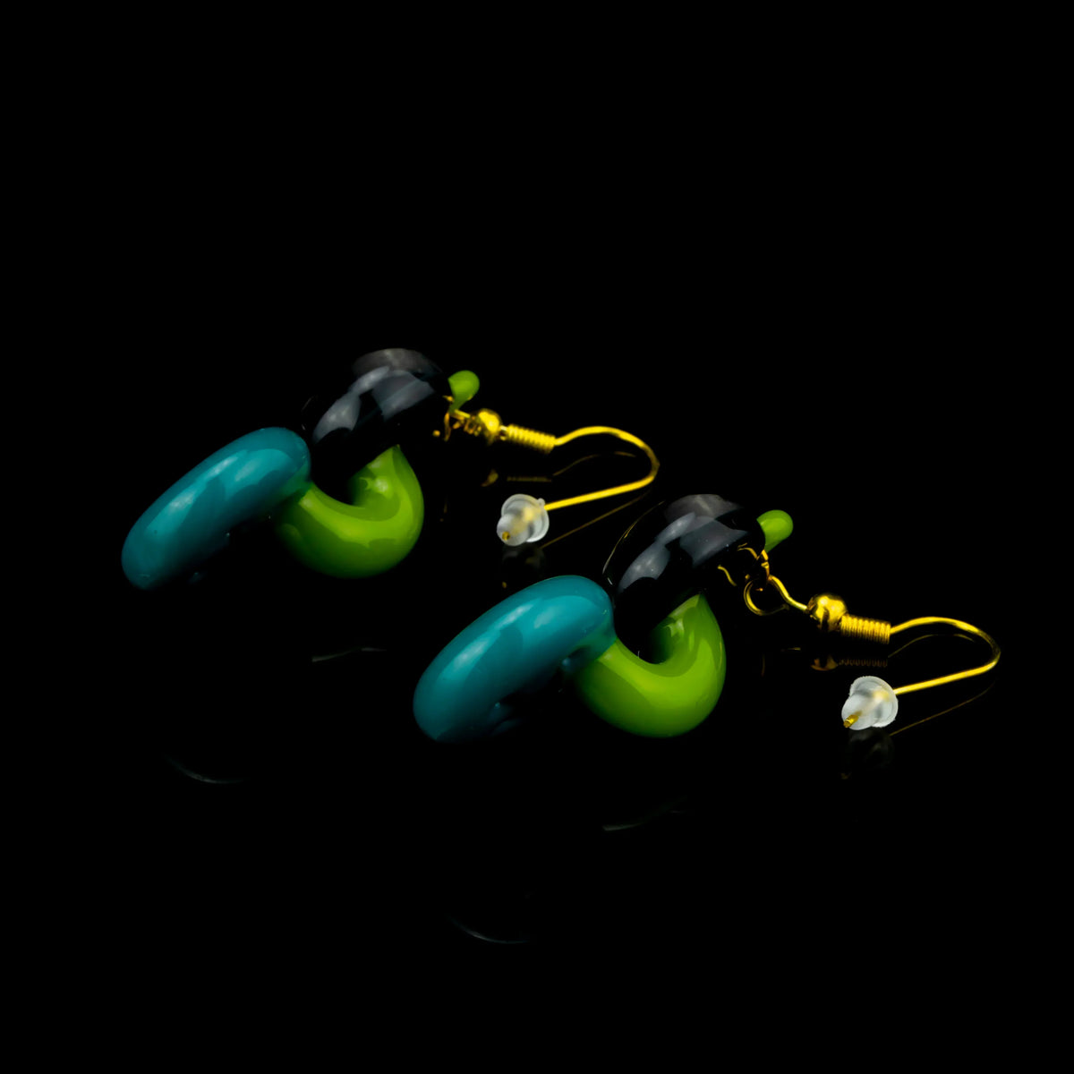 Colorful glass earrings in green, teal, and black with gold hooks on black background