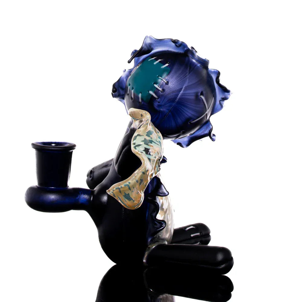 Artistic glass sitting doll pipe with blue houndstooth pattern and unique sculpted details