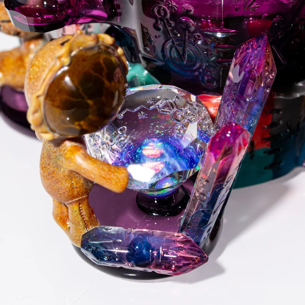 Close-up of artistic glass pipe with colorful crystals and a small figurine, heady glass detail
