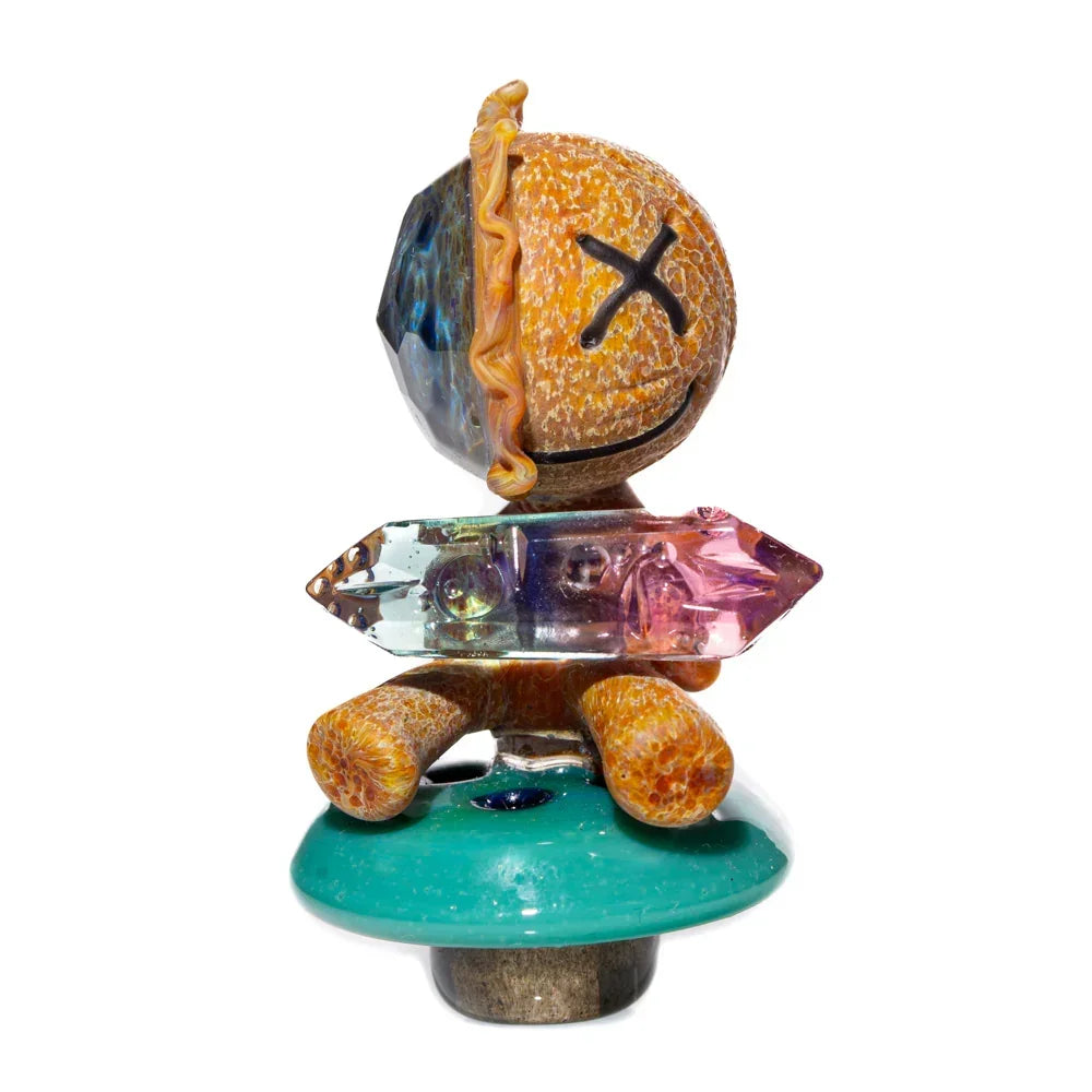 Unique heady glass art carb cap with orange figure, crystal accents, and green base on white background.