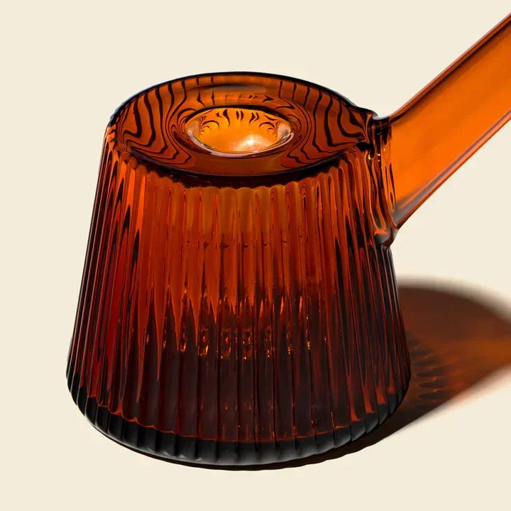 Amber glass bubbler with ribbed texture and modern design on neutral background
