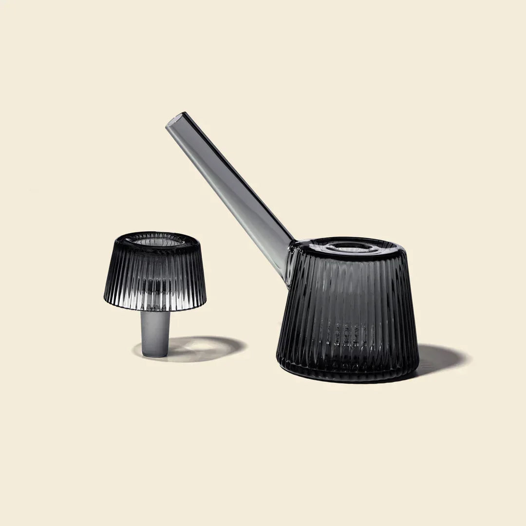 Charcoal gray glass bubbler pipe with ribbed design and matching glass insert on beige background