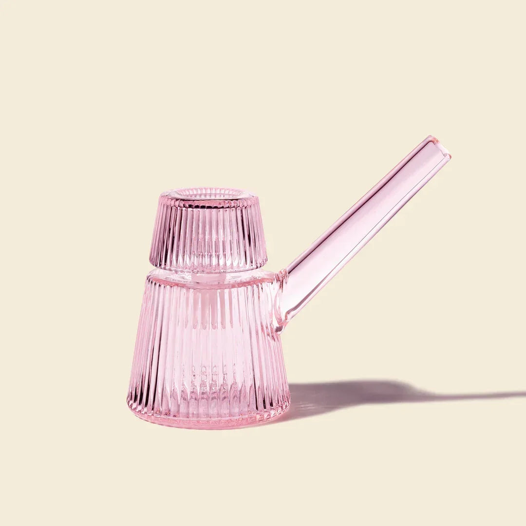 Pink ribbed glass bubbler with petal design on a beige background