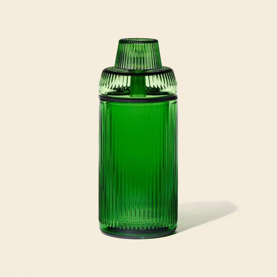 Emerald green ribbed glass gravity bong on beige background