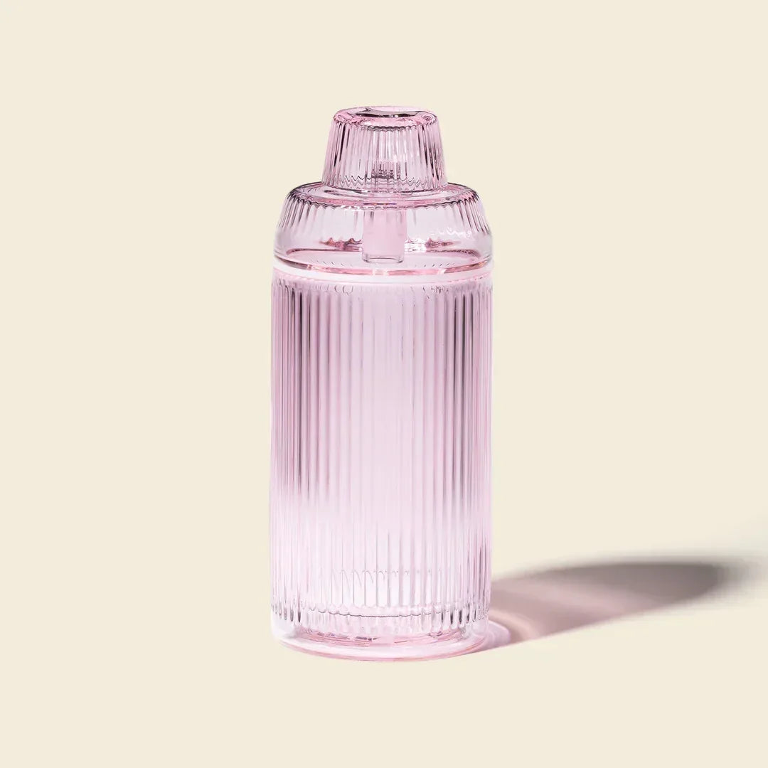 Pink ribbed glass gravity bong with modern design on a neutral background