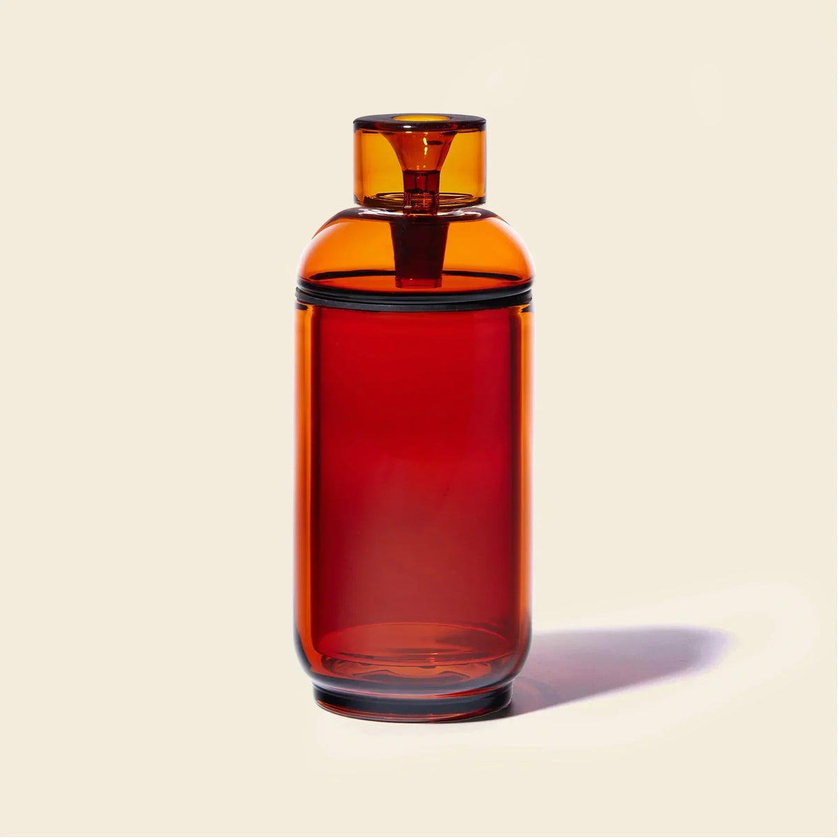 Amber glass gravity bong with cylindrical shape on a light background